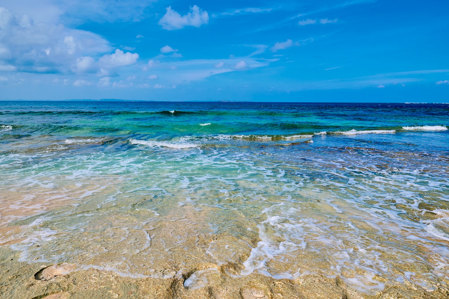 Strandszene mit blauem Meer und weißen Wellen