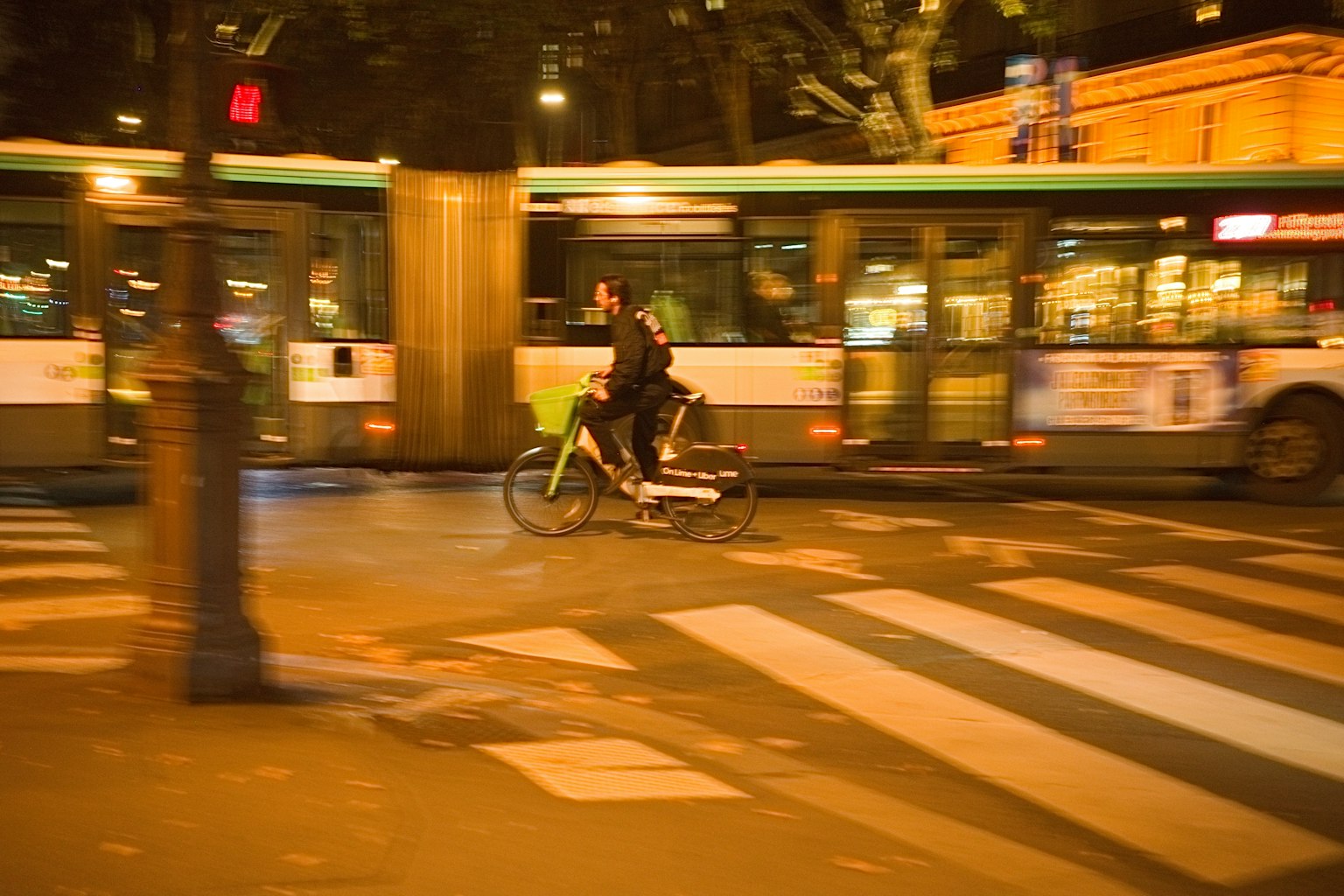 Una persona in bicicletta in un contesto urbano con un autobus in movimento