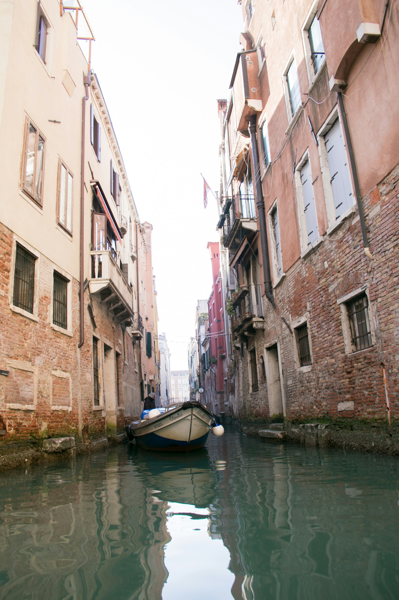 Schmaler Kanal in Venedig mit einem festgemachten Boot und historischen Gebäuden