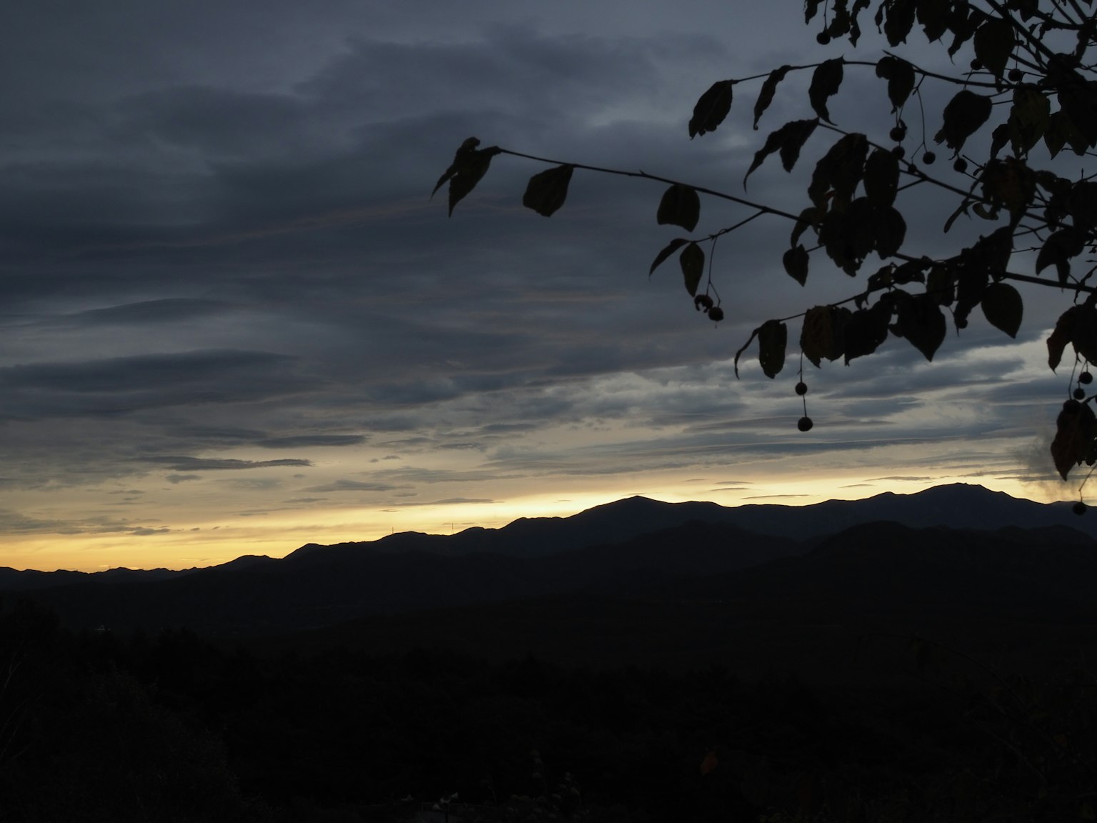 Silhouette von Bergen vor einem dunklen Himmel mit Sonnenuntergangsnuancen