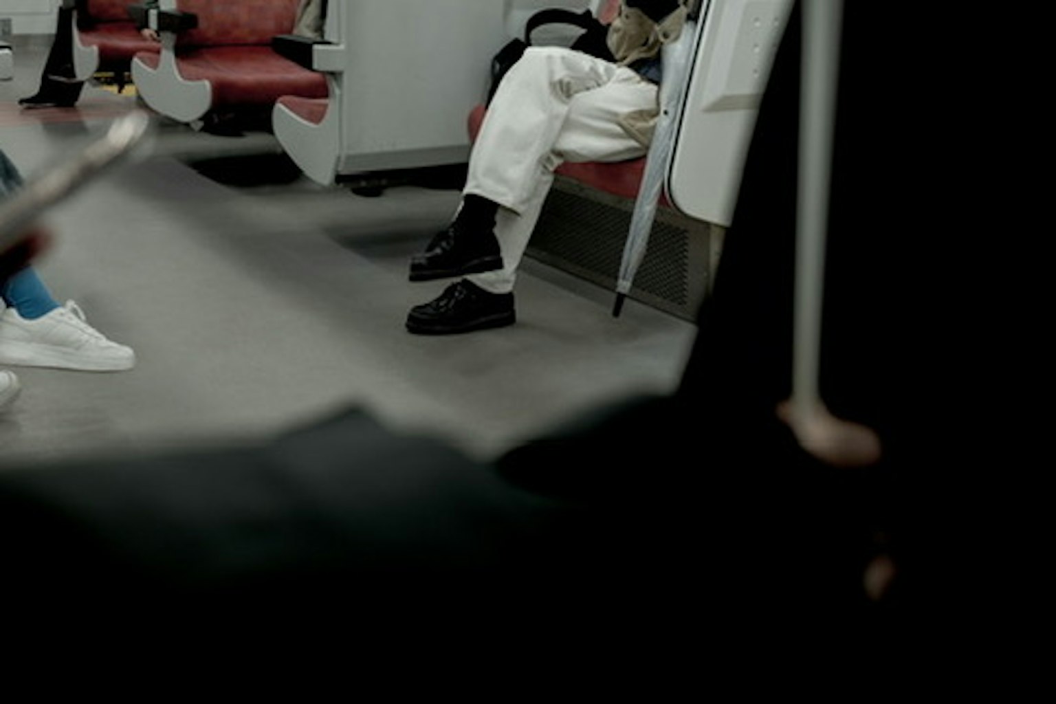 Escena que muestra los pies de personas en un vagón de metro