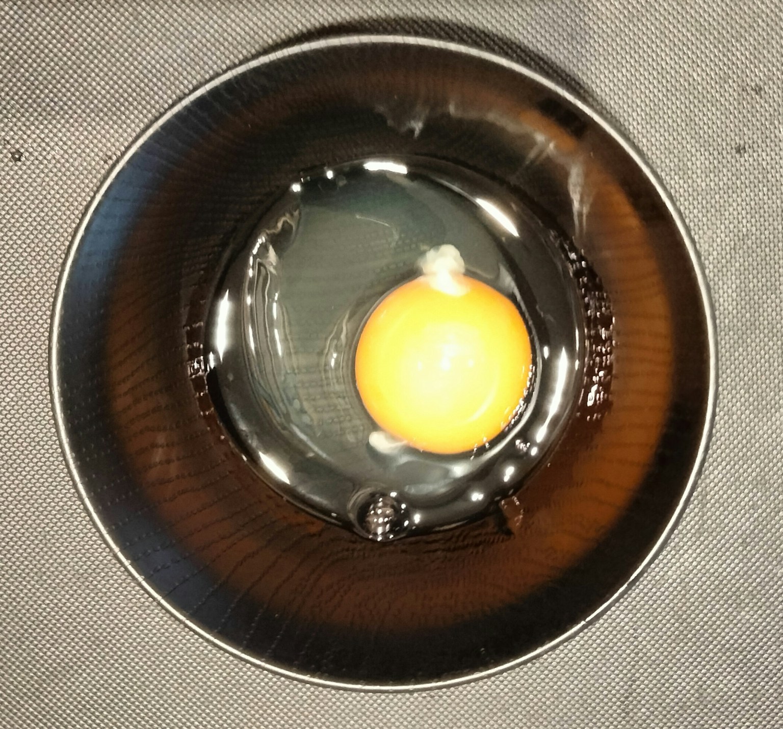 Kuning telur dalam mangkuk gelap dengan cairan transparan