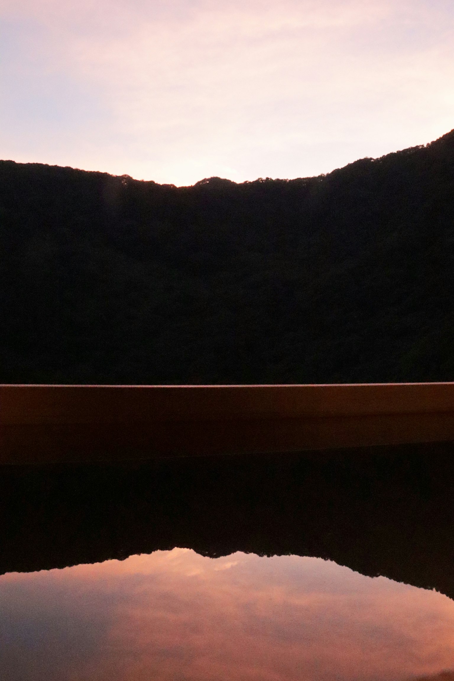 ทะเลสาบสงบที่สะท้อนสีพระอาทิตย์ตกพร้อมกับเงาของภูเขา