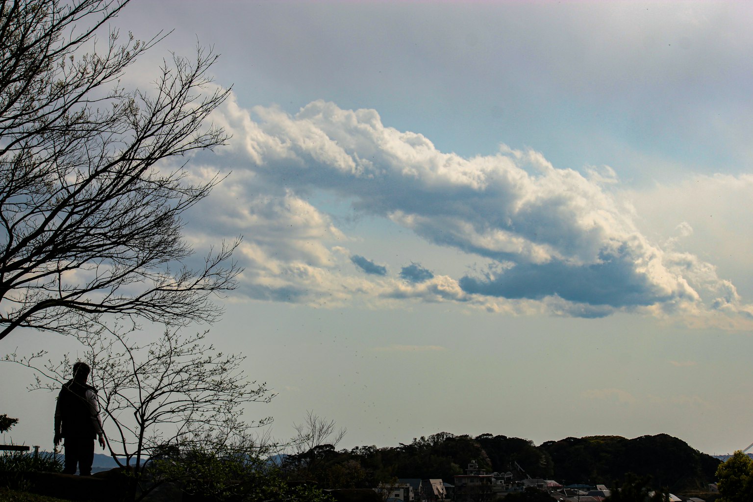 Silhouette d'une personne se tenant contre un ciel dramatique avec des nuages