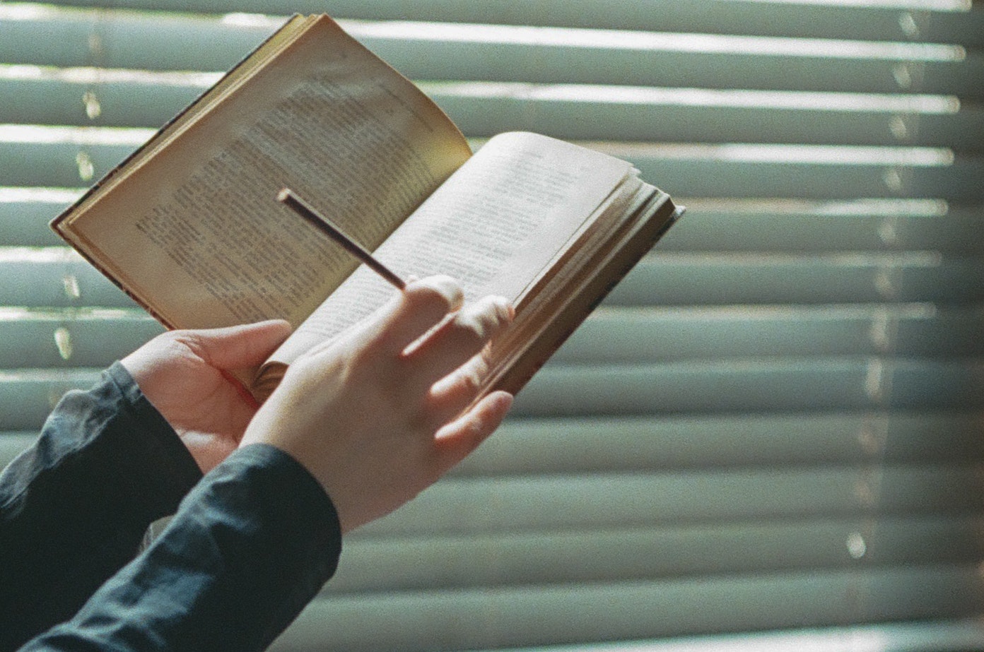 open book in hands by a window with soft light