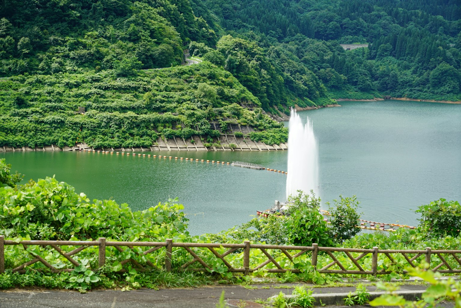 Vue pittoresque d'un lac avec une fontaine entourée de collines verdoyantes