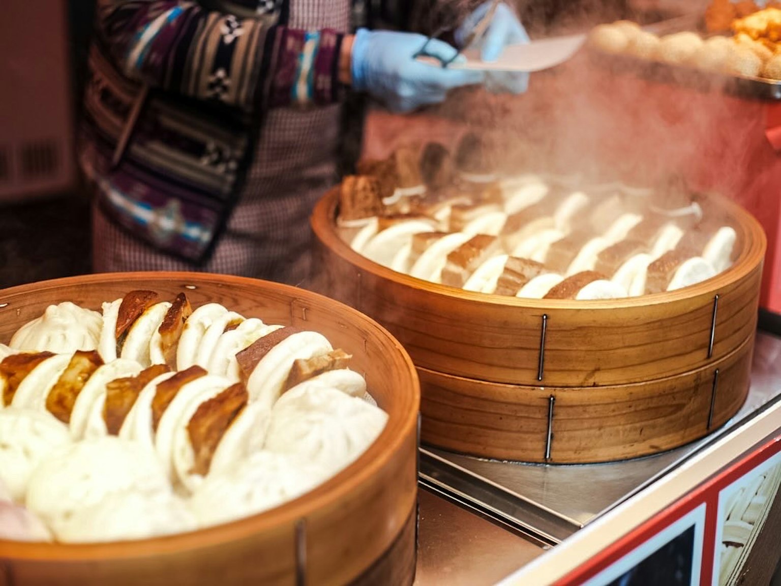 Bun kukus dalam kukusan bambu dengan uap yang naik di warung makanan