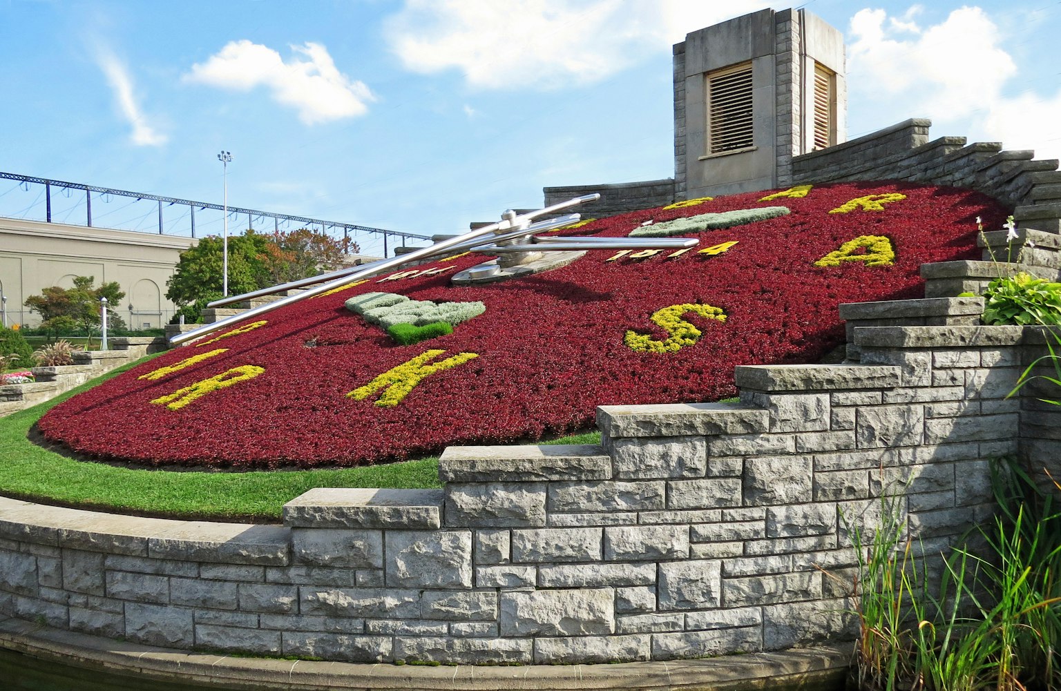Grand jardin de fleurs en forme d'horloge avec des motifs floraux colorés et un aménagement en pierre
