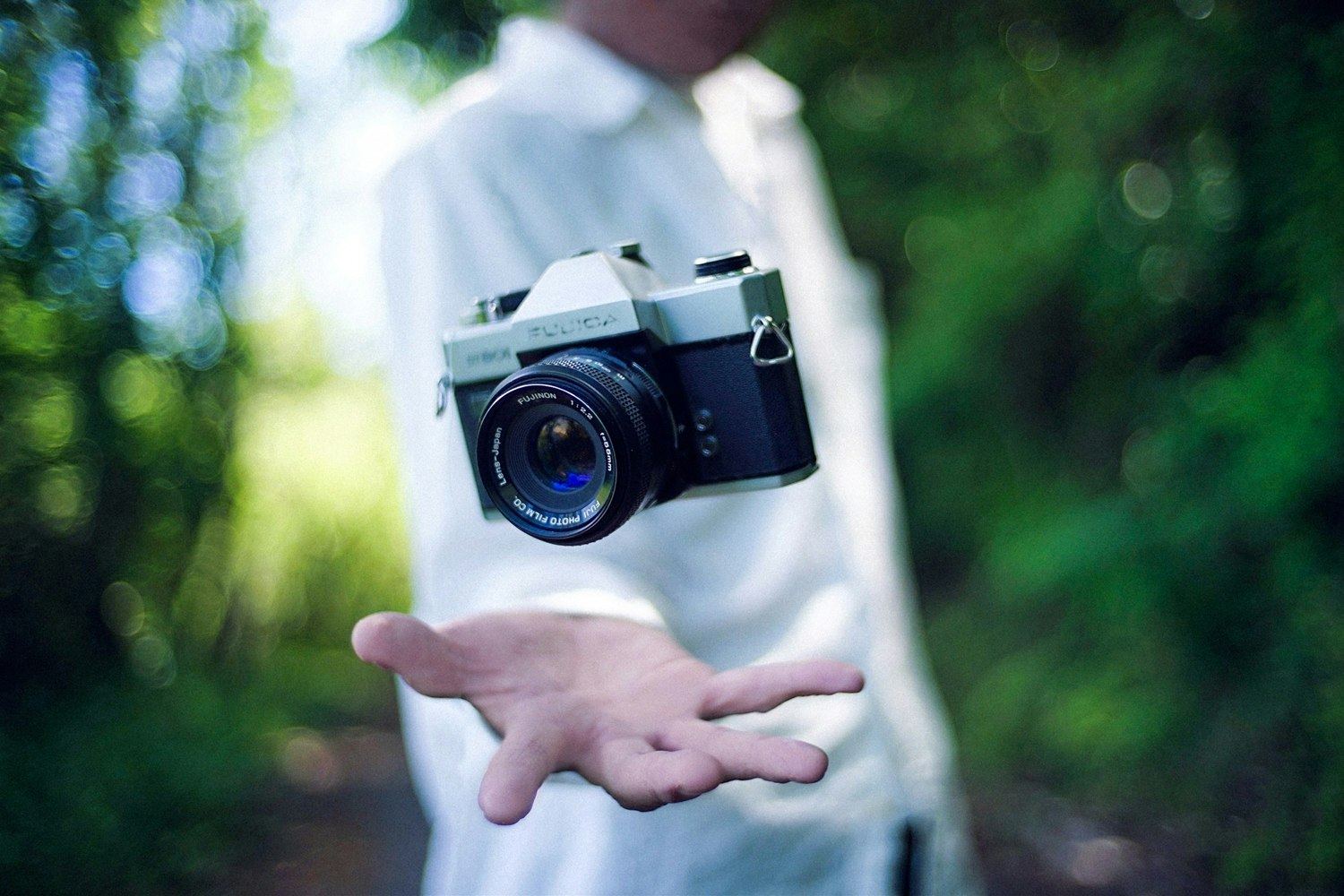 手のひらにフィルムカメラを持つ人物