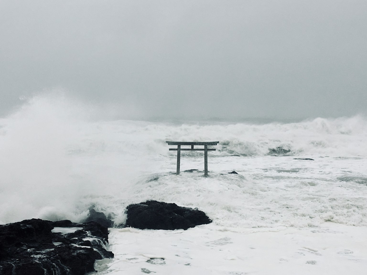 A striking scene of rough sea and a torii gate