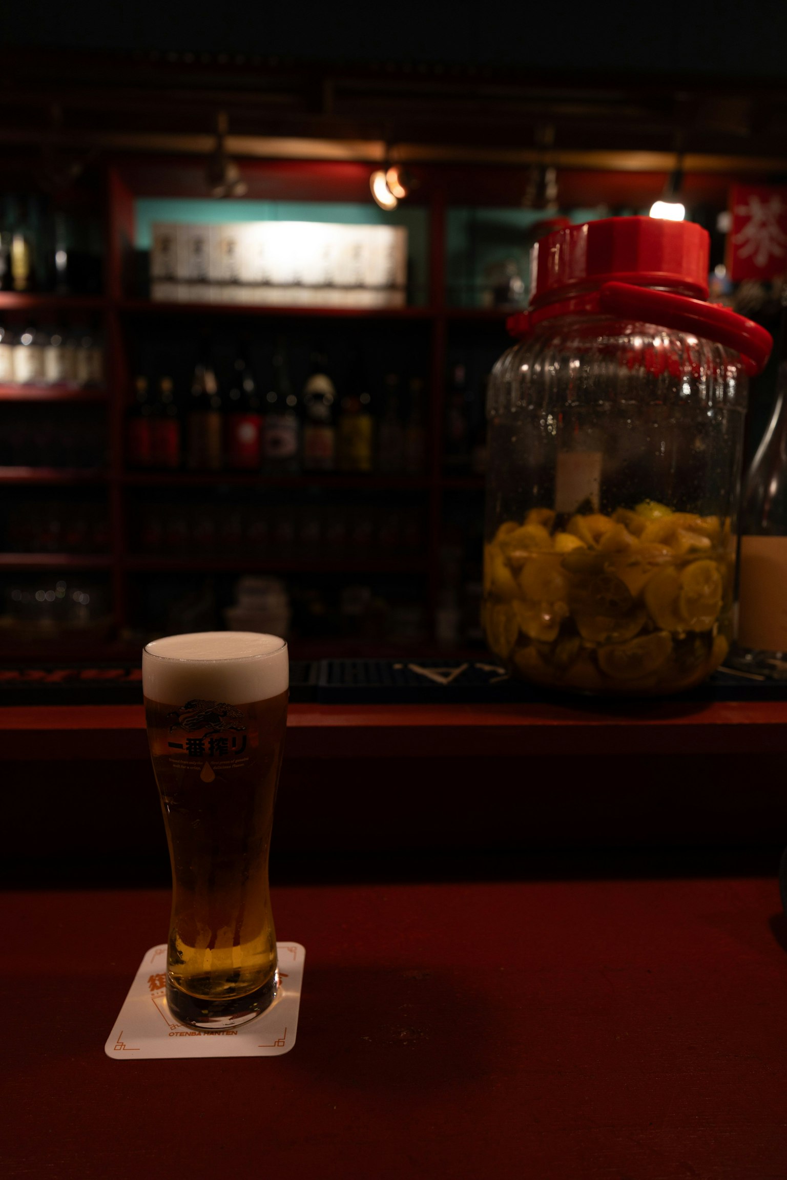 Un verre de bière et un pot de fruits sur un comptoir de bar