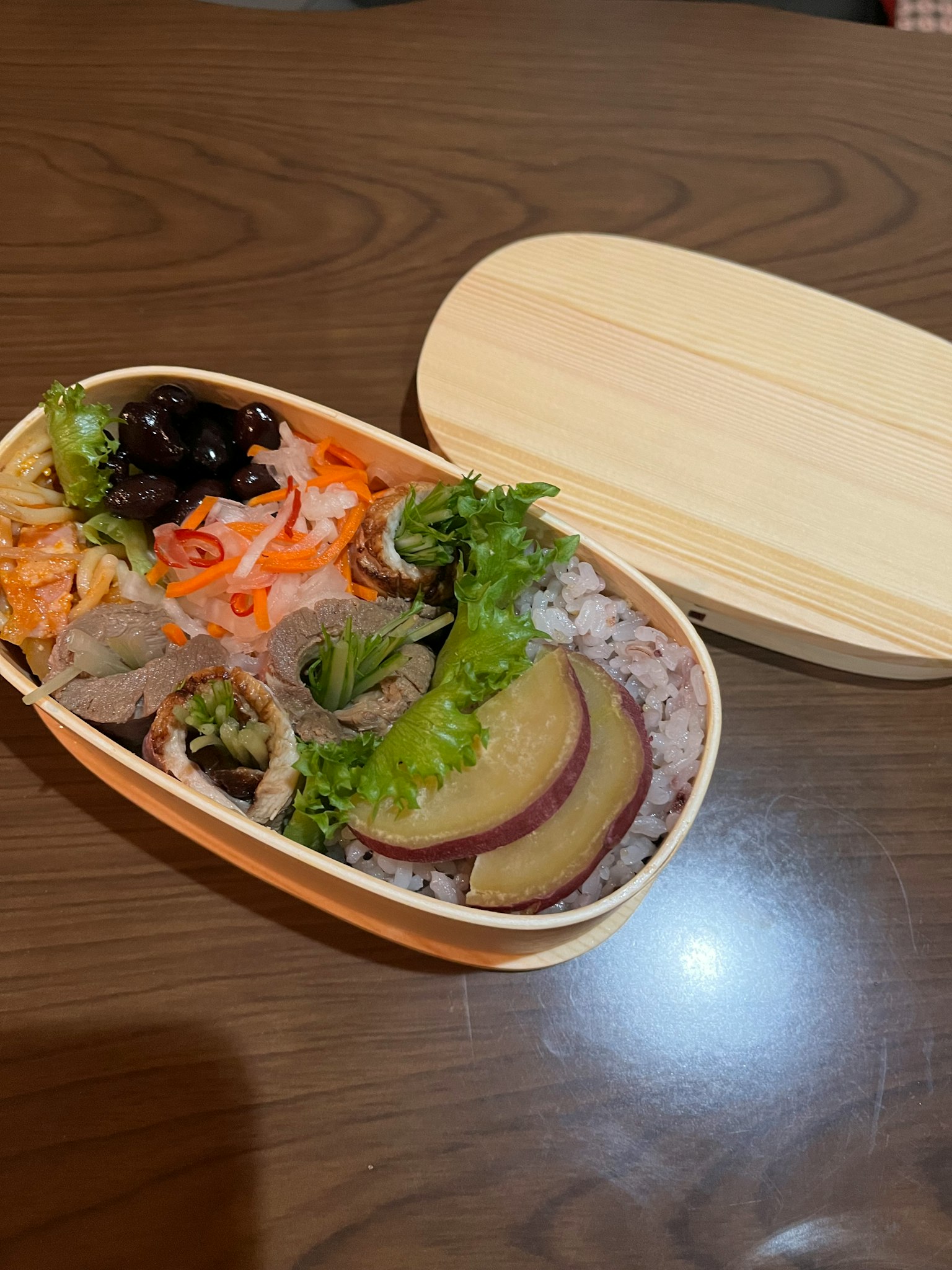 A bento box filled with various dishes and colorful vegetables