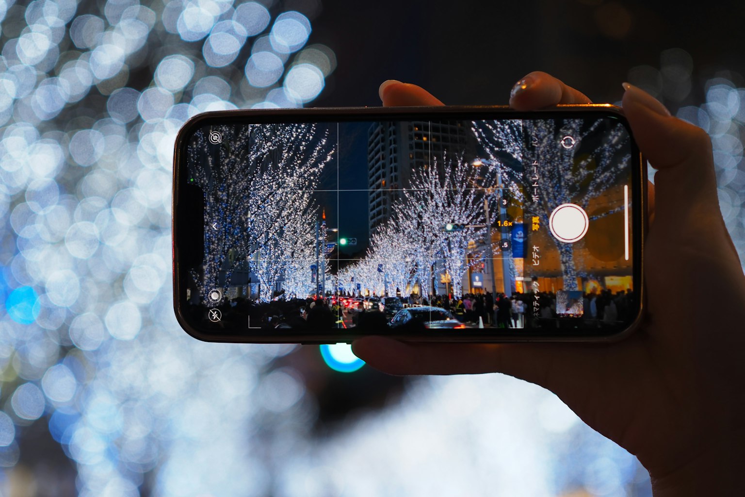 Ein Smartphone, das die nächtlichen Lichter der Stadt mit beleuchteten Bäumen aufnimmt