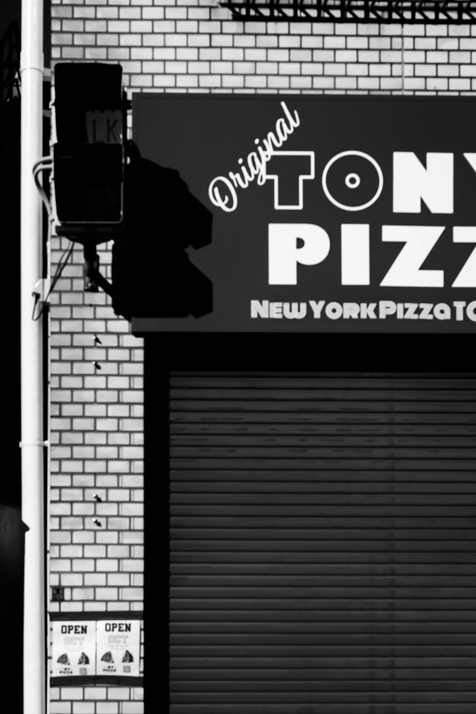 Eksterior hitam putih Pizzeria Tony dengan tanda yang mencolok