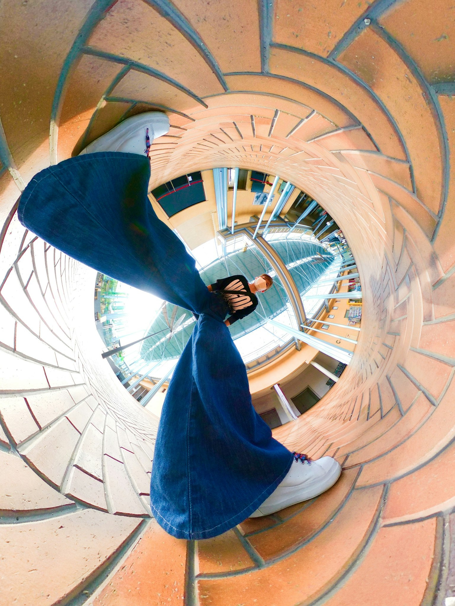 Scatto a figura intera di una persona in piedi in un motivo di piastrelle a spirale