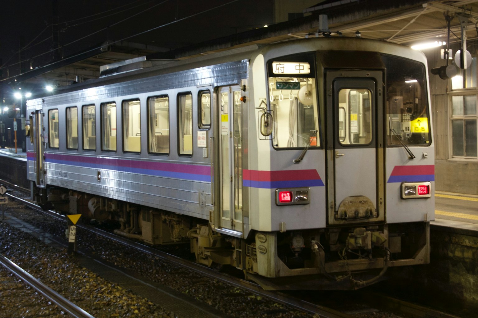 Zugwagen an einer Station bei Nacht mit beleuchteten Fenstern