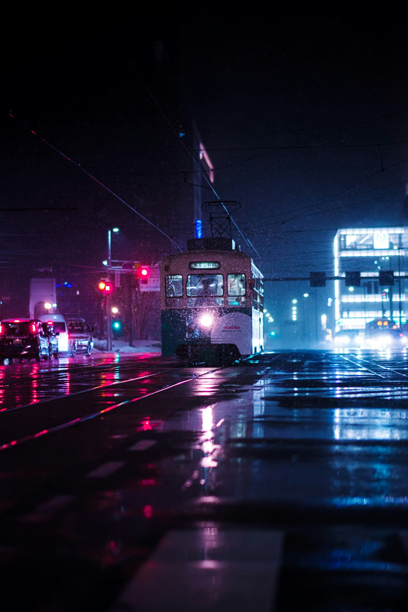 Area halte bus malam hari di Toyama, neon memantul di jalan bersalju
