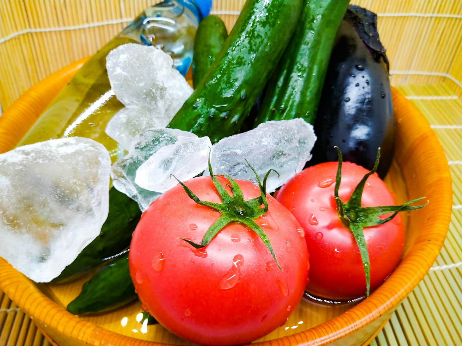 Eine Schüssel voller frischer Gemüse einschließlich Tomaten Gurken und Auberginen sowie Eiswürfeln