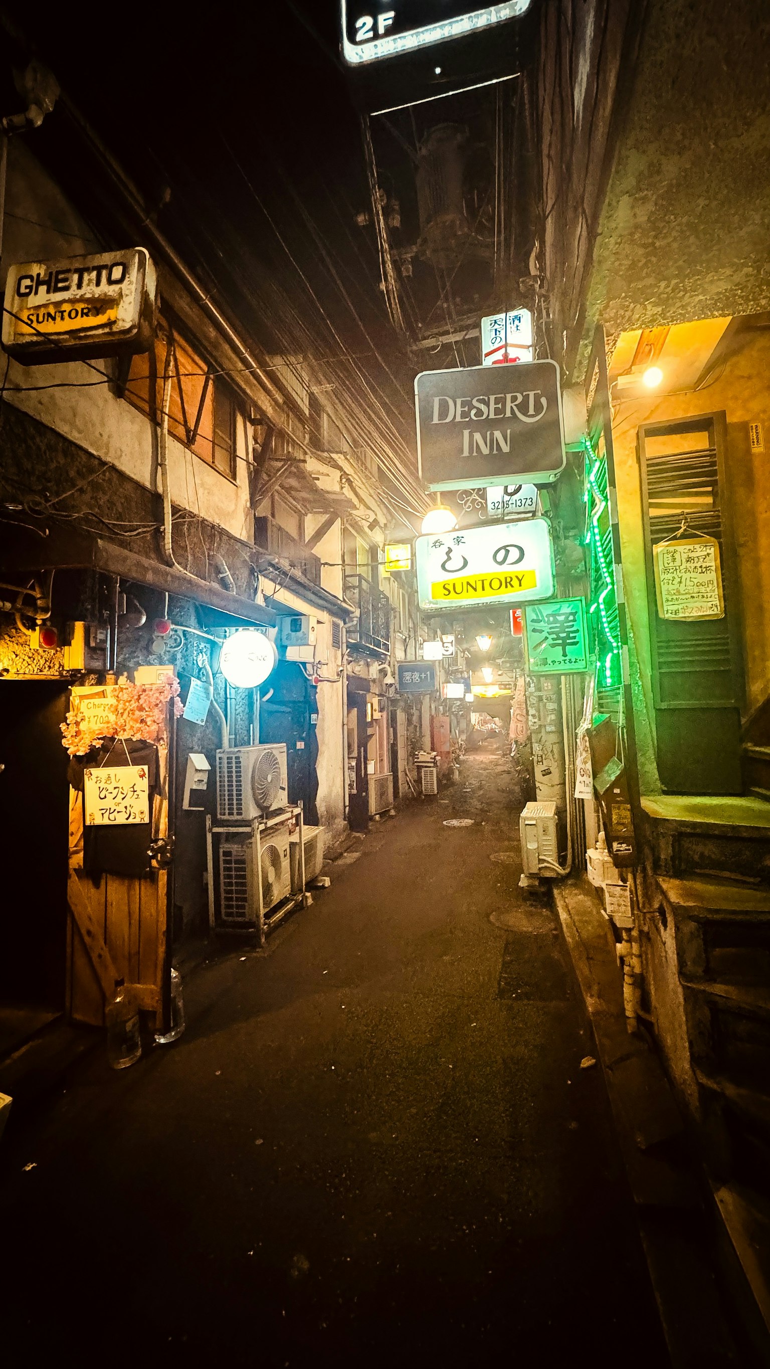 夜の狭い路地にあるネオン看板と店舗の様子