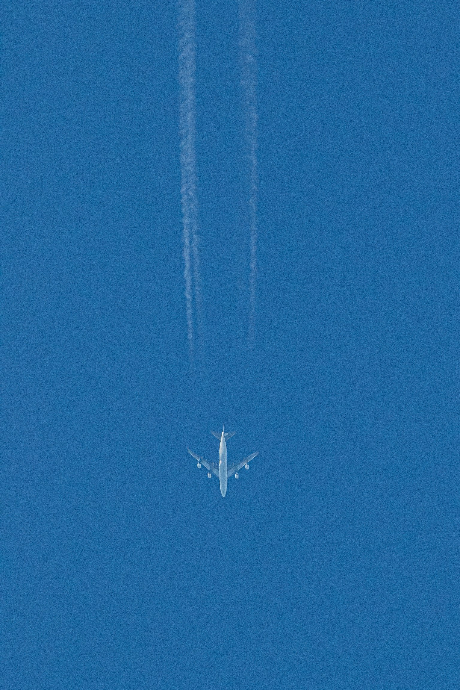 Aereo passeggeri che vola in un cielo blu chiaro lasciando scie