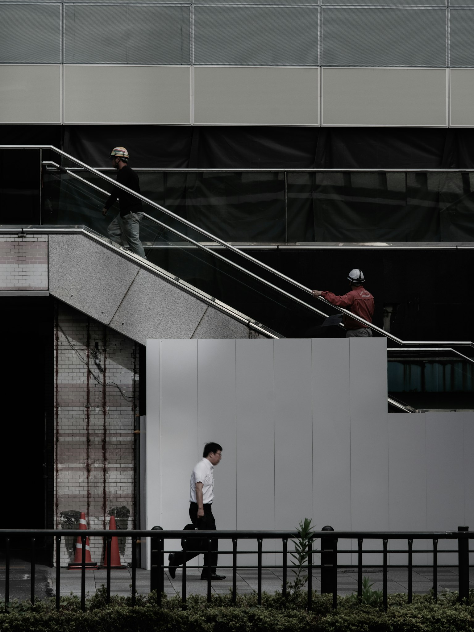 建筑外部的两名工人和一名路人的照片