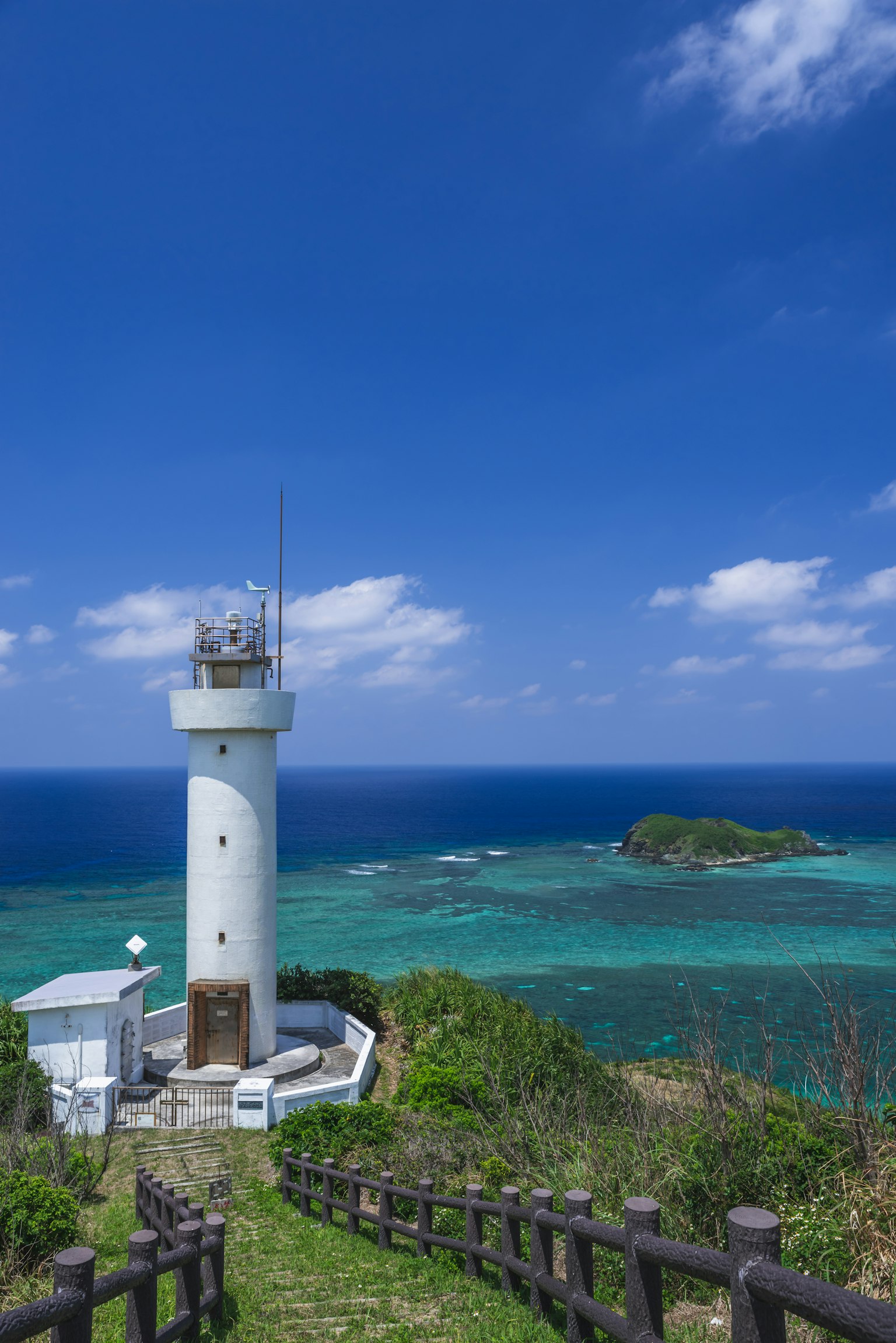 Lighthouse overlooking the blue sea and sky with green hills