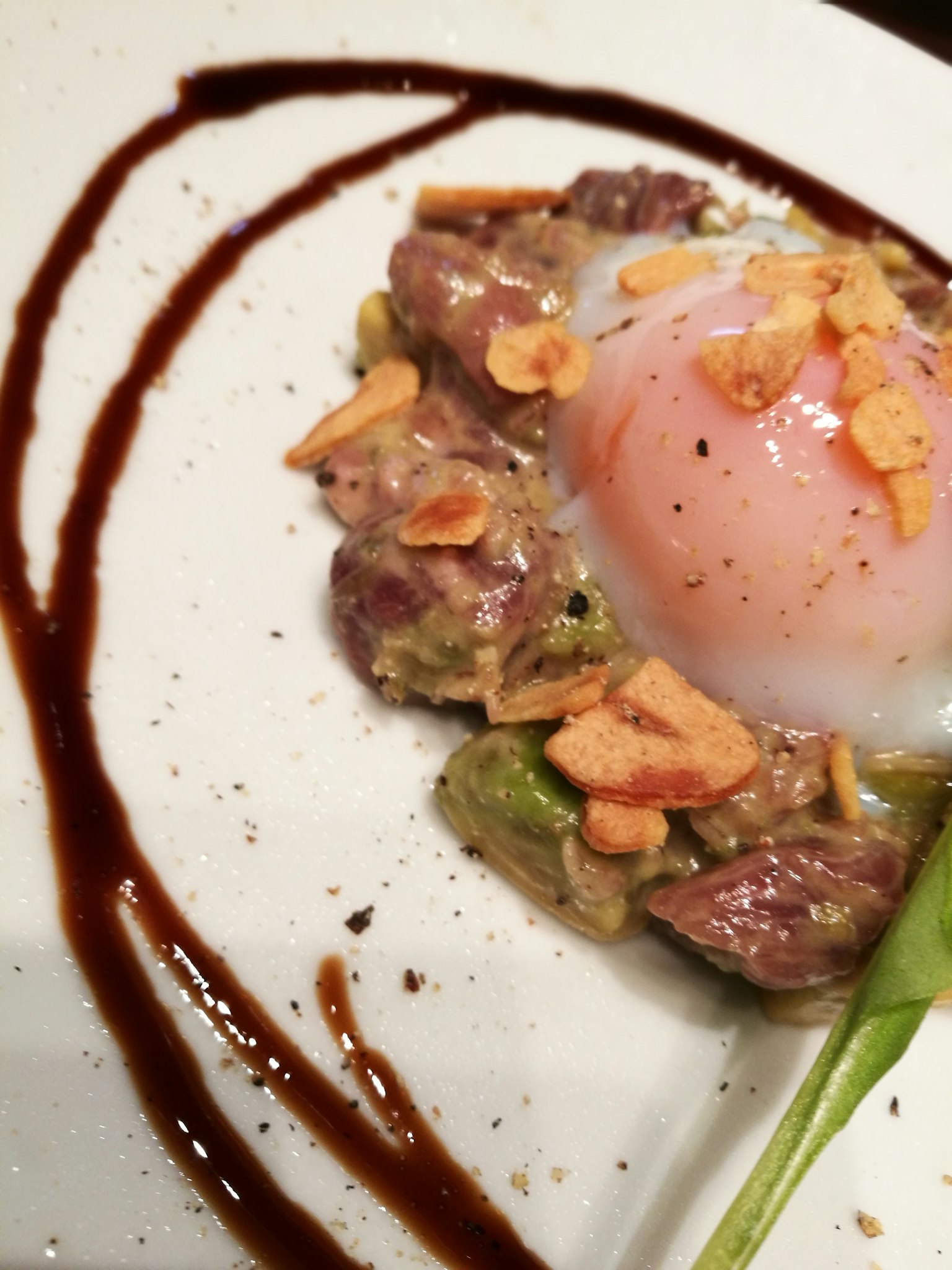 Un plato bellamente presentado con huevo poche y carne de res decorado con chips de ajo