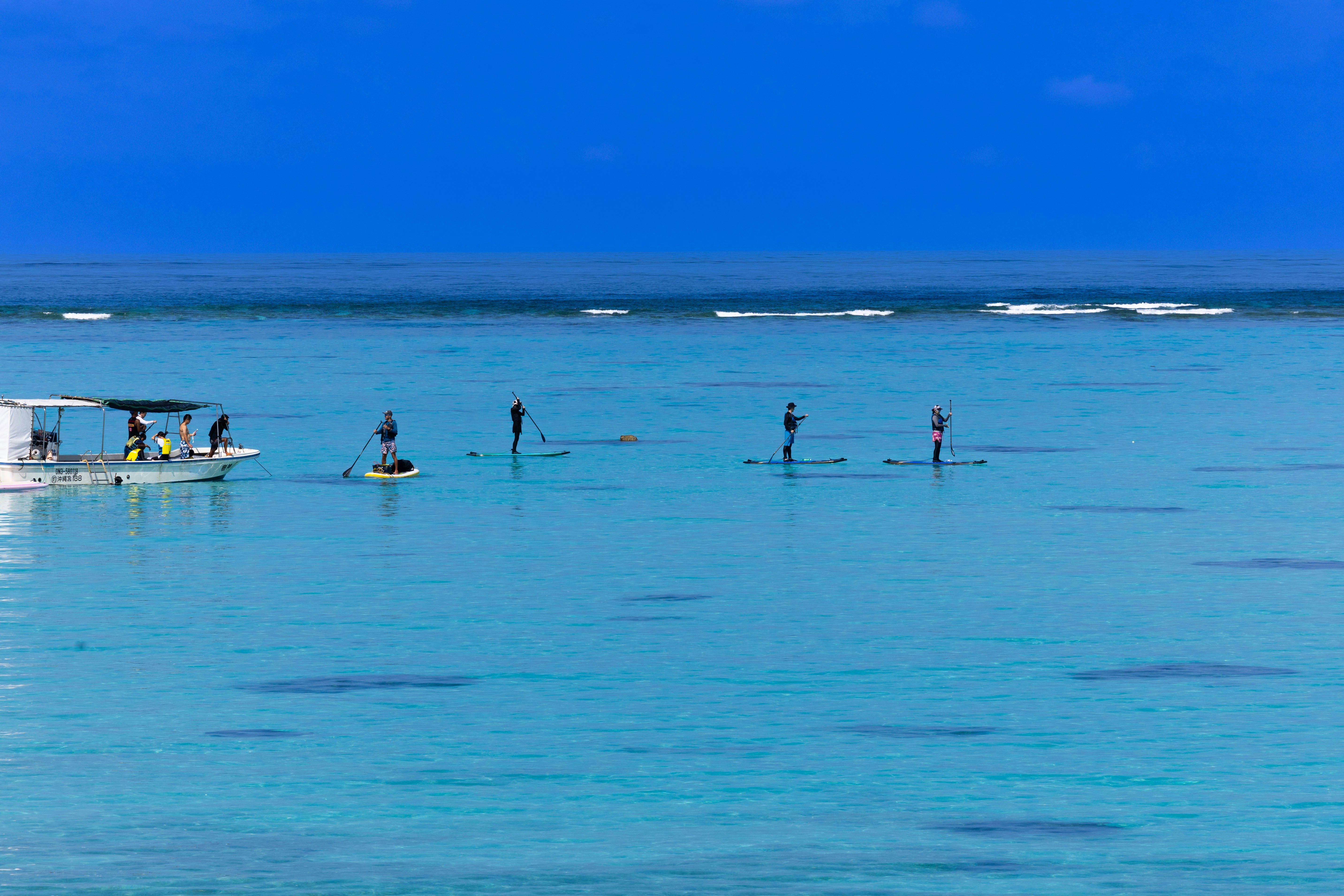 桟橋の先で泳ぐ人々がいる青い海の風景