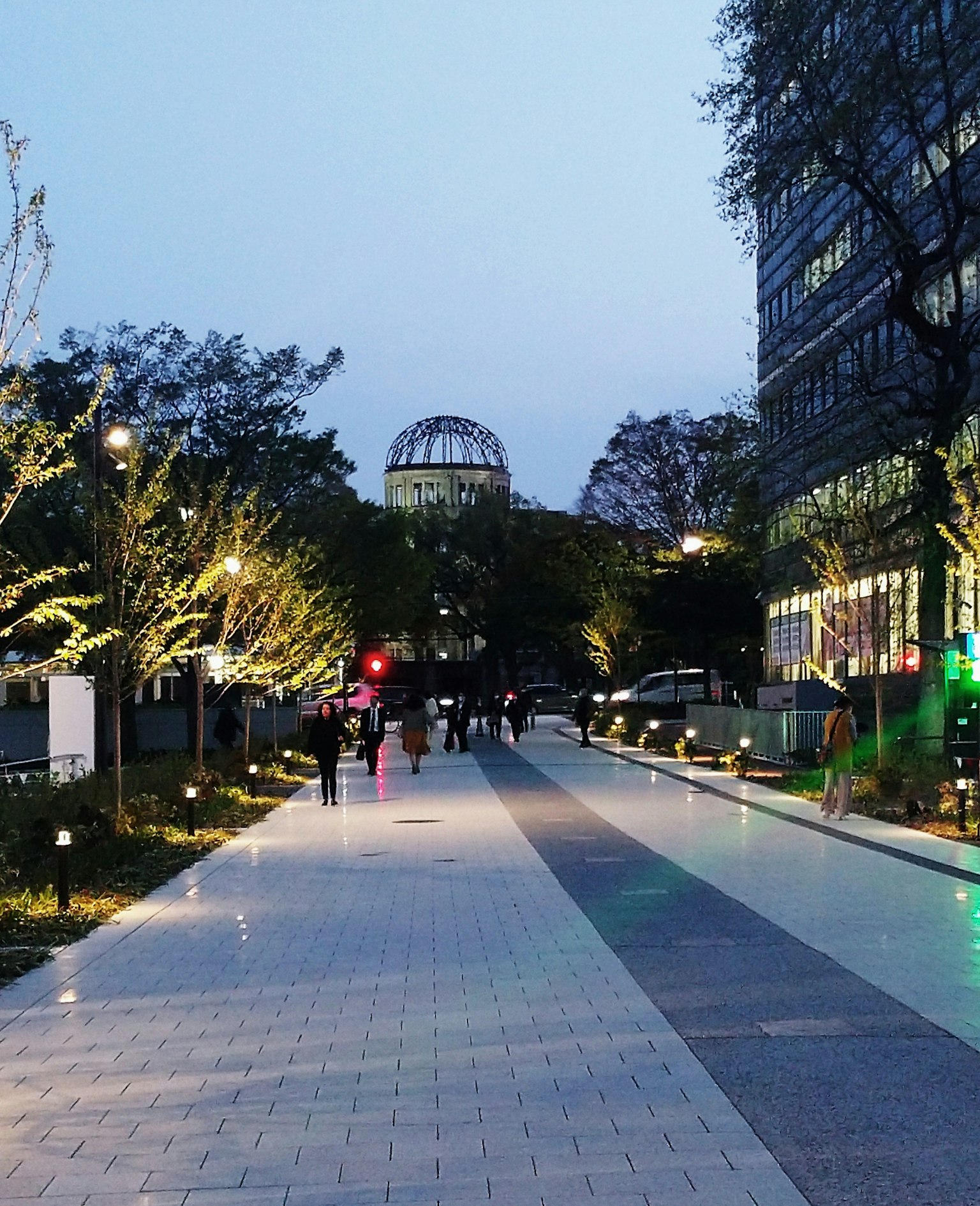 Paysage urbain au crépuscule avec des arbres et des bâtiments des personnes marchant éclairées par des lampadaires
