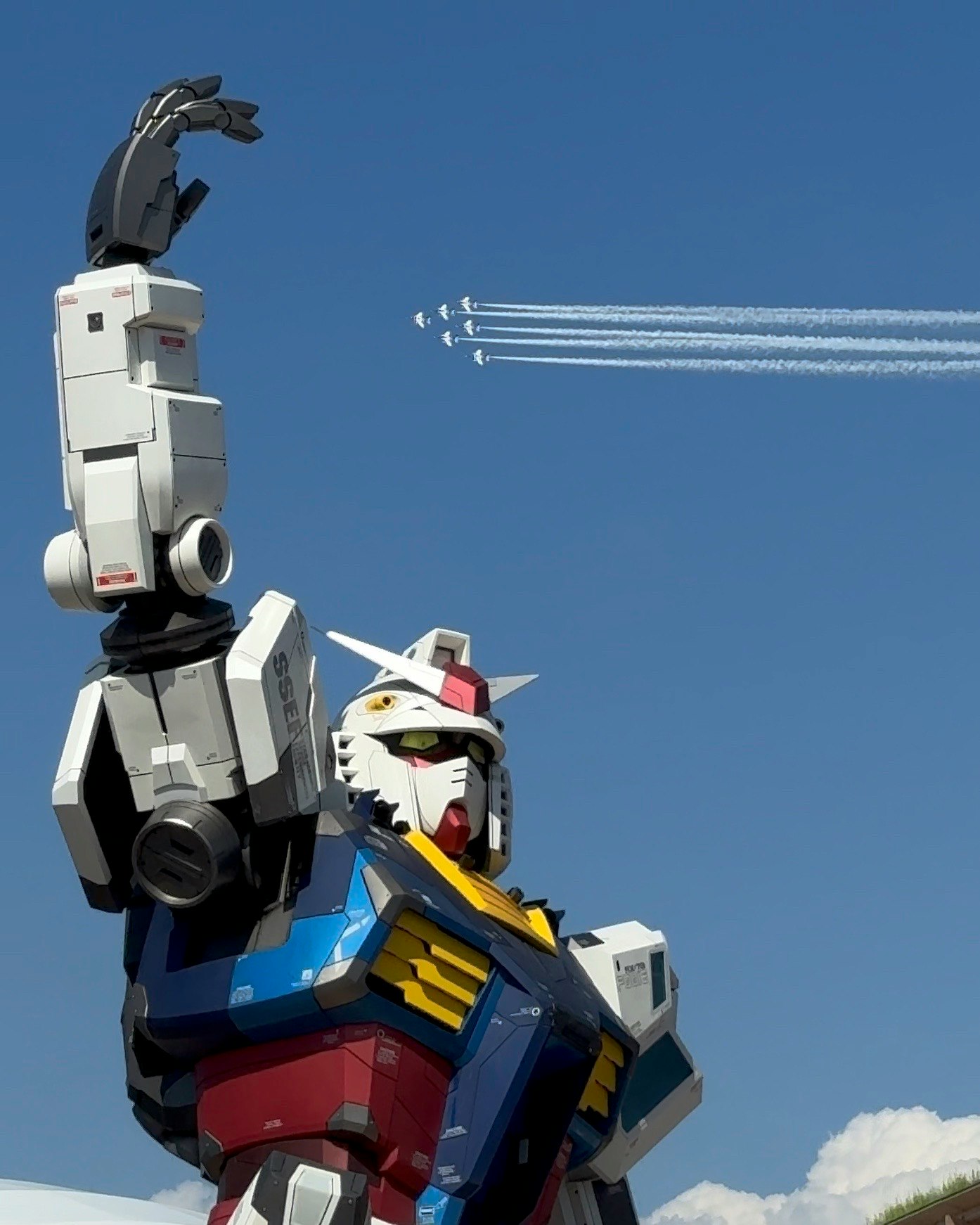 青空の下で立つ巨大なロボットの頭部と武装