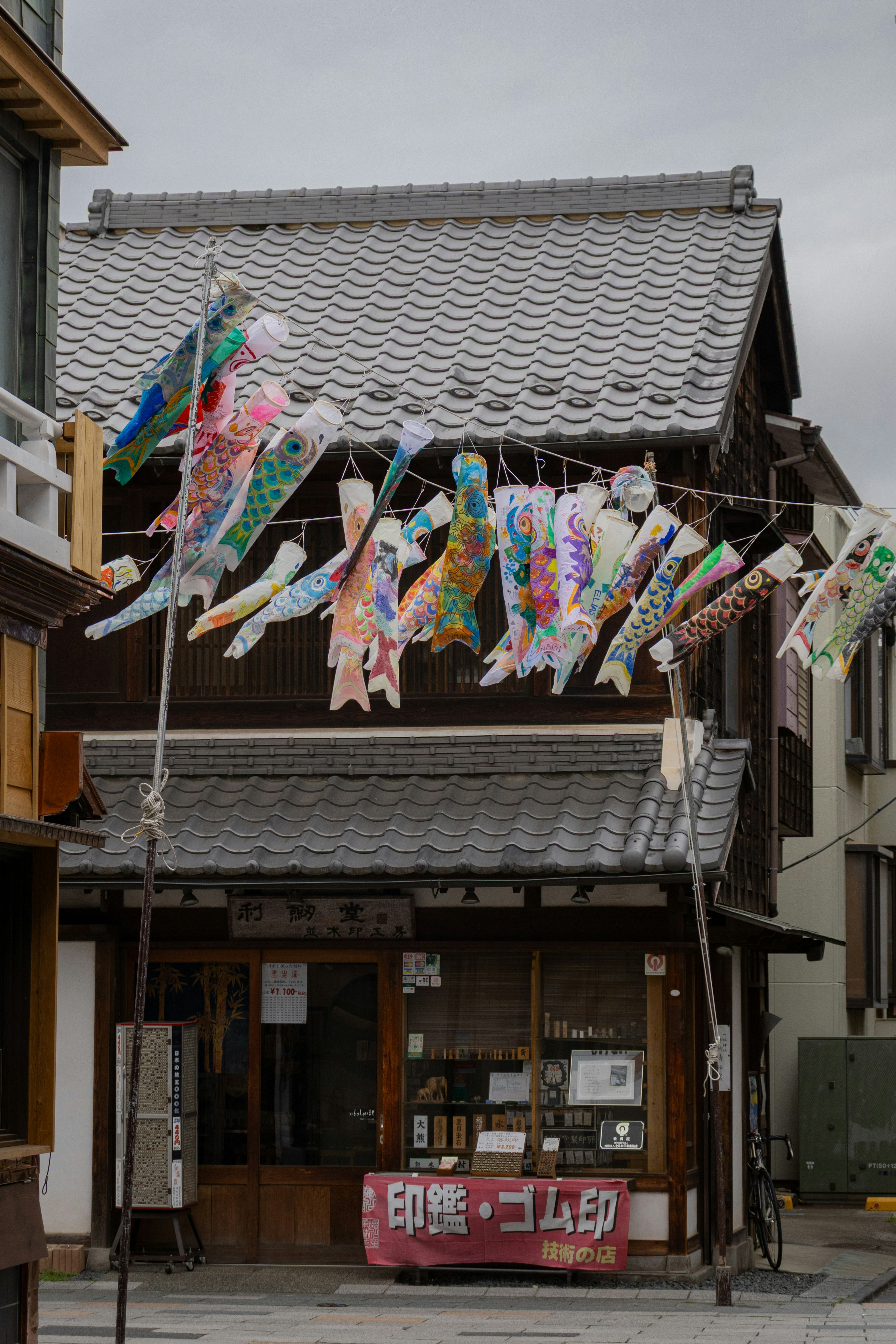 鯉のぼりが並ぶ町家の軒先の春の風景