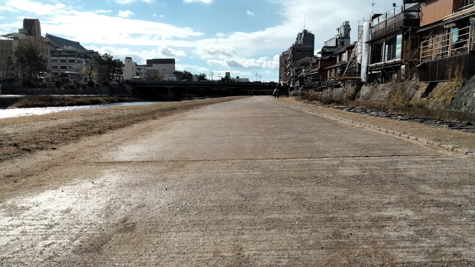 Camino de concreto junto a un río con cielo azul