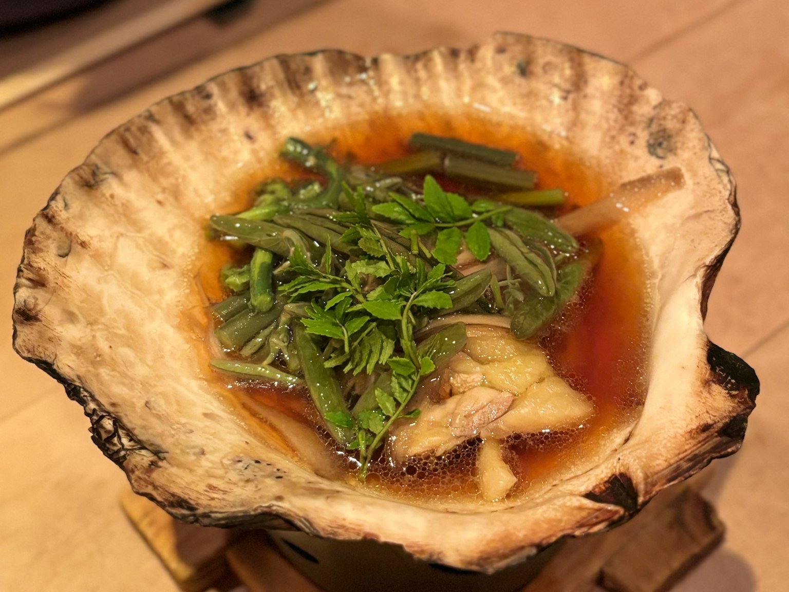 汤盛在贝壳中，配有新鲜的绿叶蔬菜