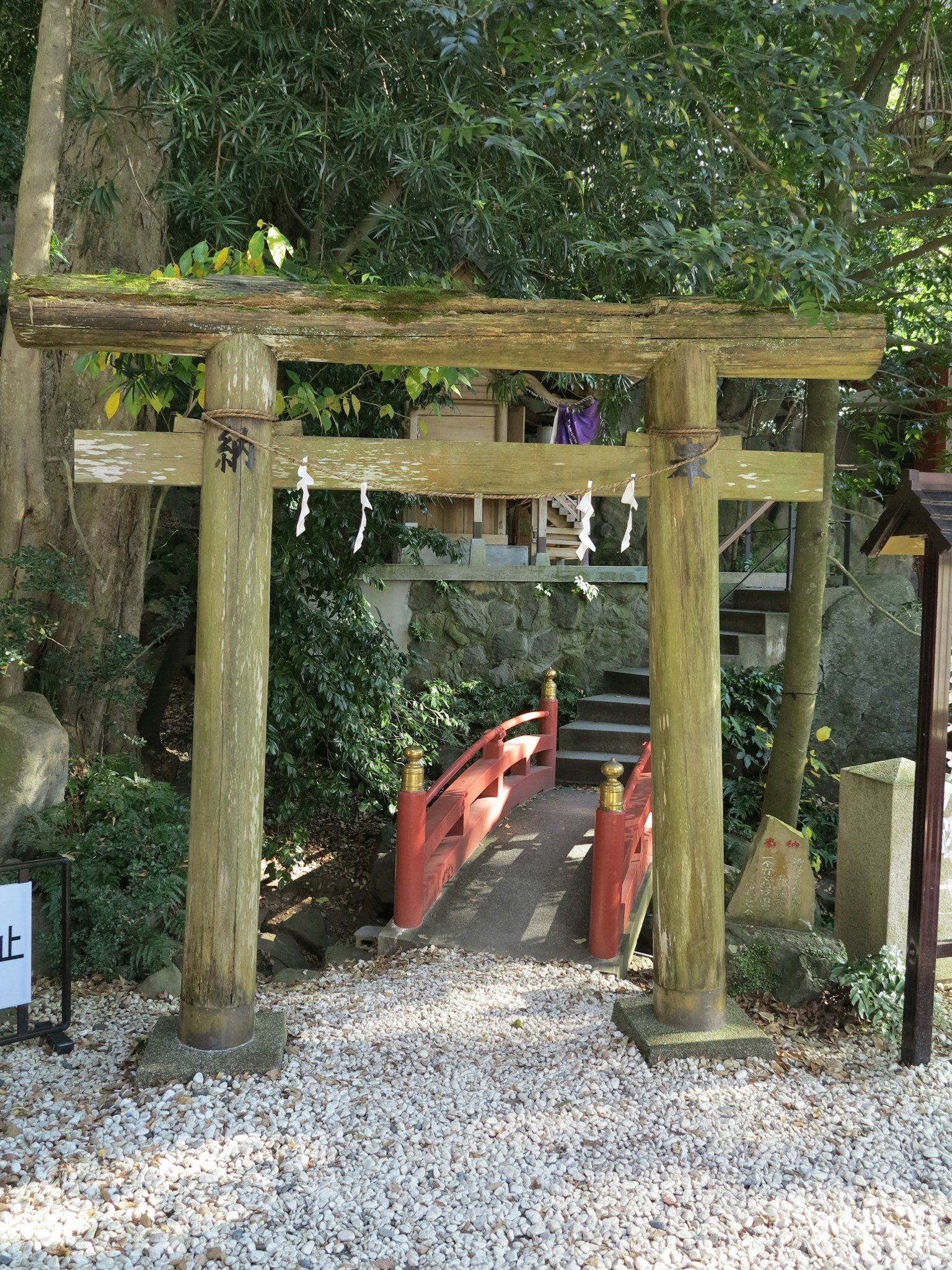 Eine ruhige Landschaft mit einem Torii und einer roten Brücke, umgeben von üppigem Grün