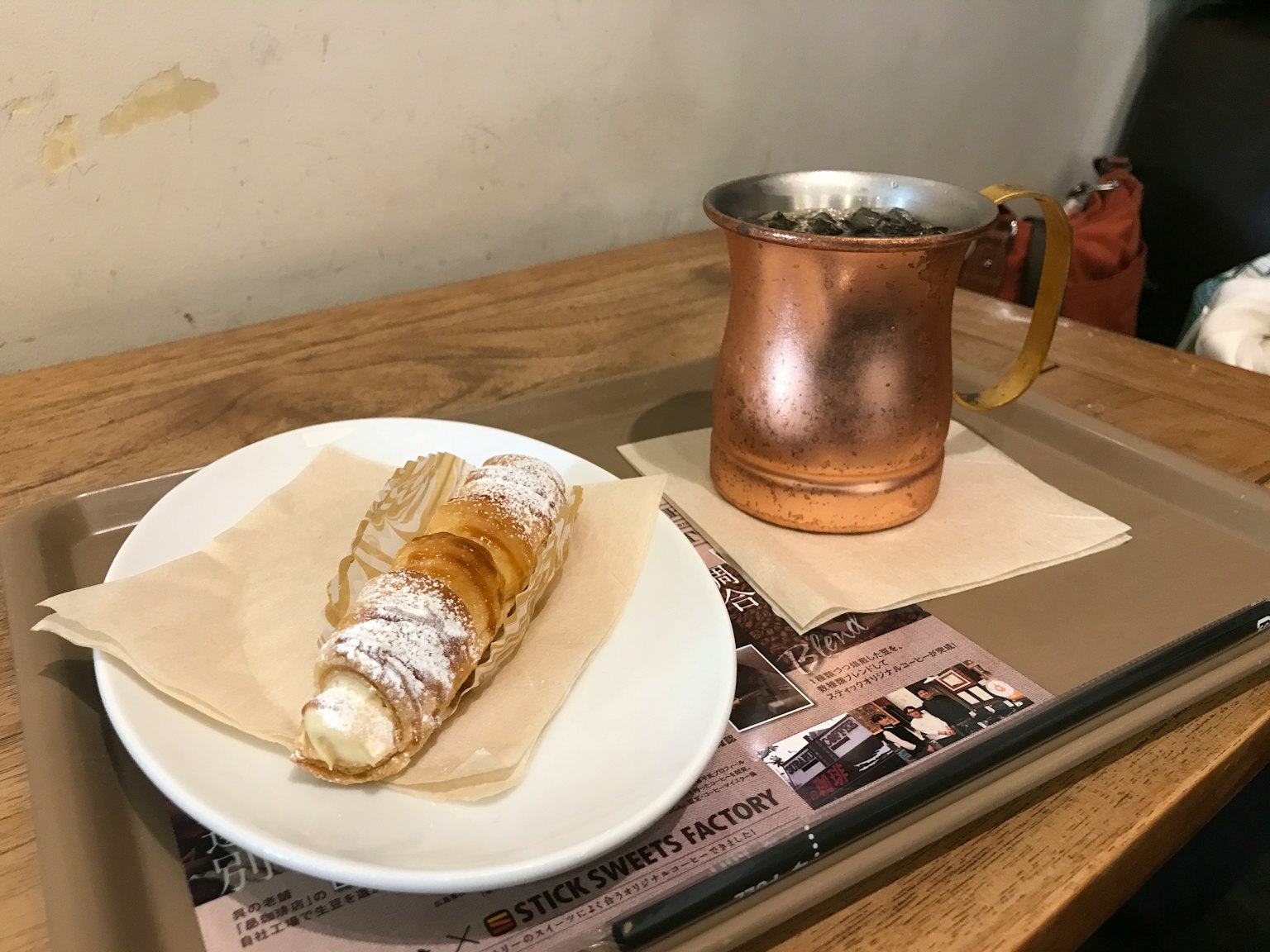 Pastel relleno de crema dulce y recipiente de bebida de cobre