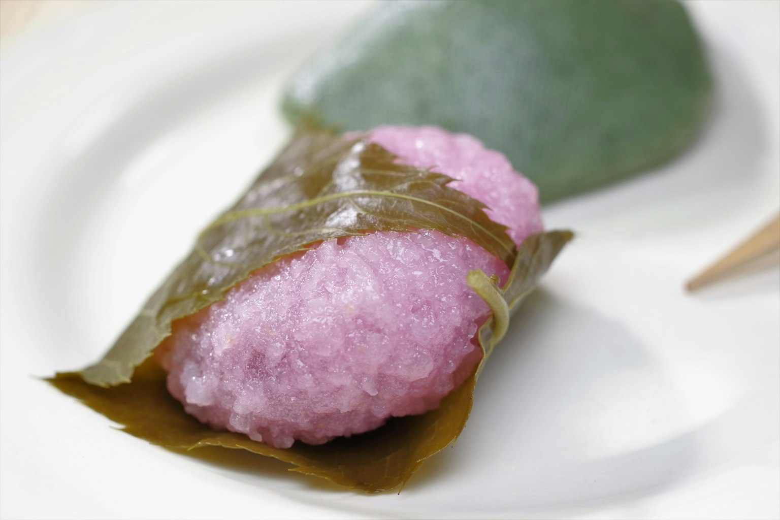 Una hermosa presentación de dulces japoneses rosados envueltos en hojas verdes