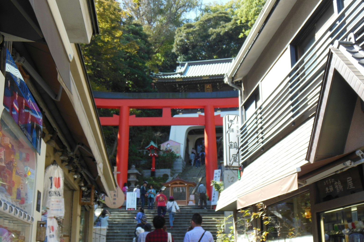 Treppen zu einem Schrein mit einem roten Torii und umliegenden Gebäuden