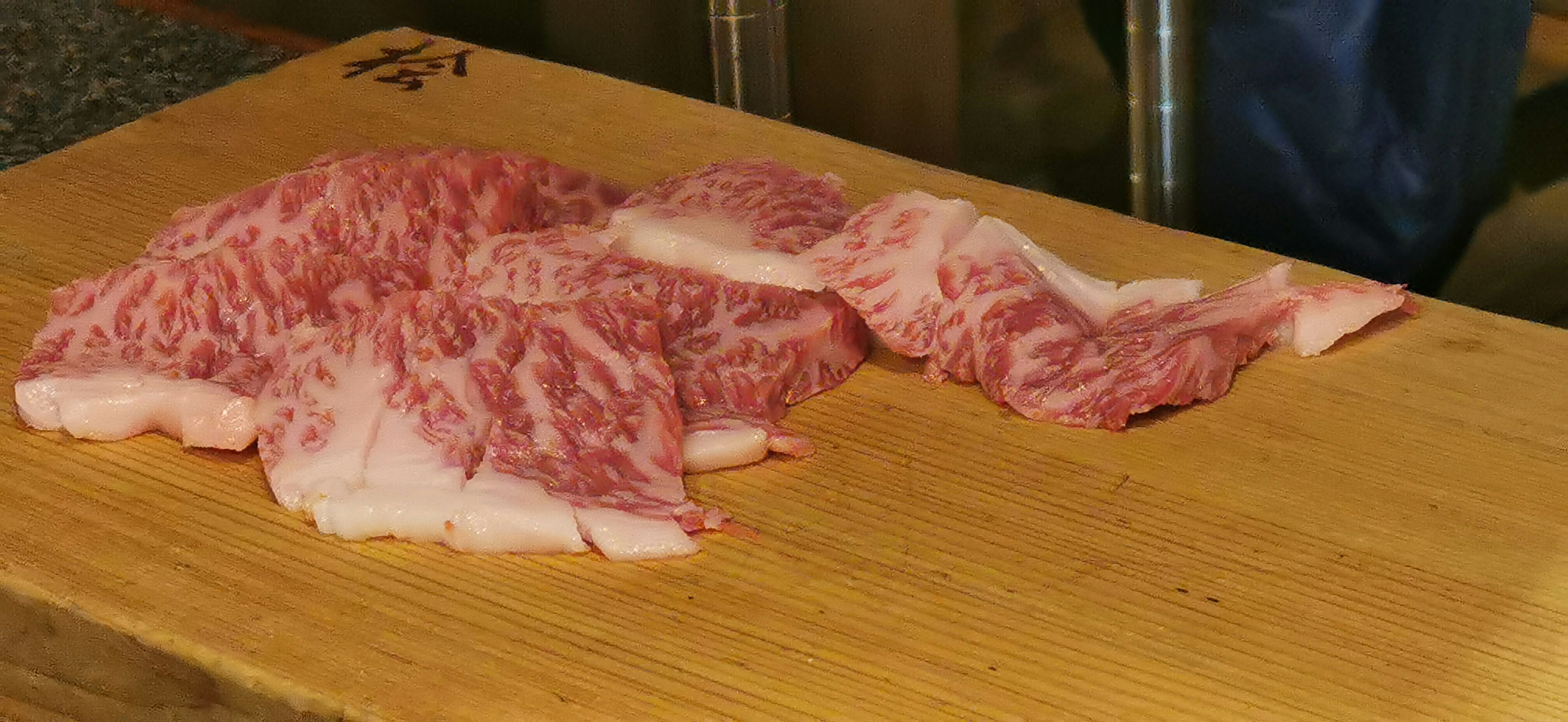 marbled beef slices on a wooden cutting board