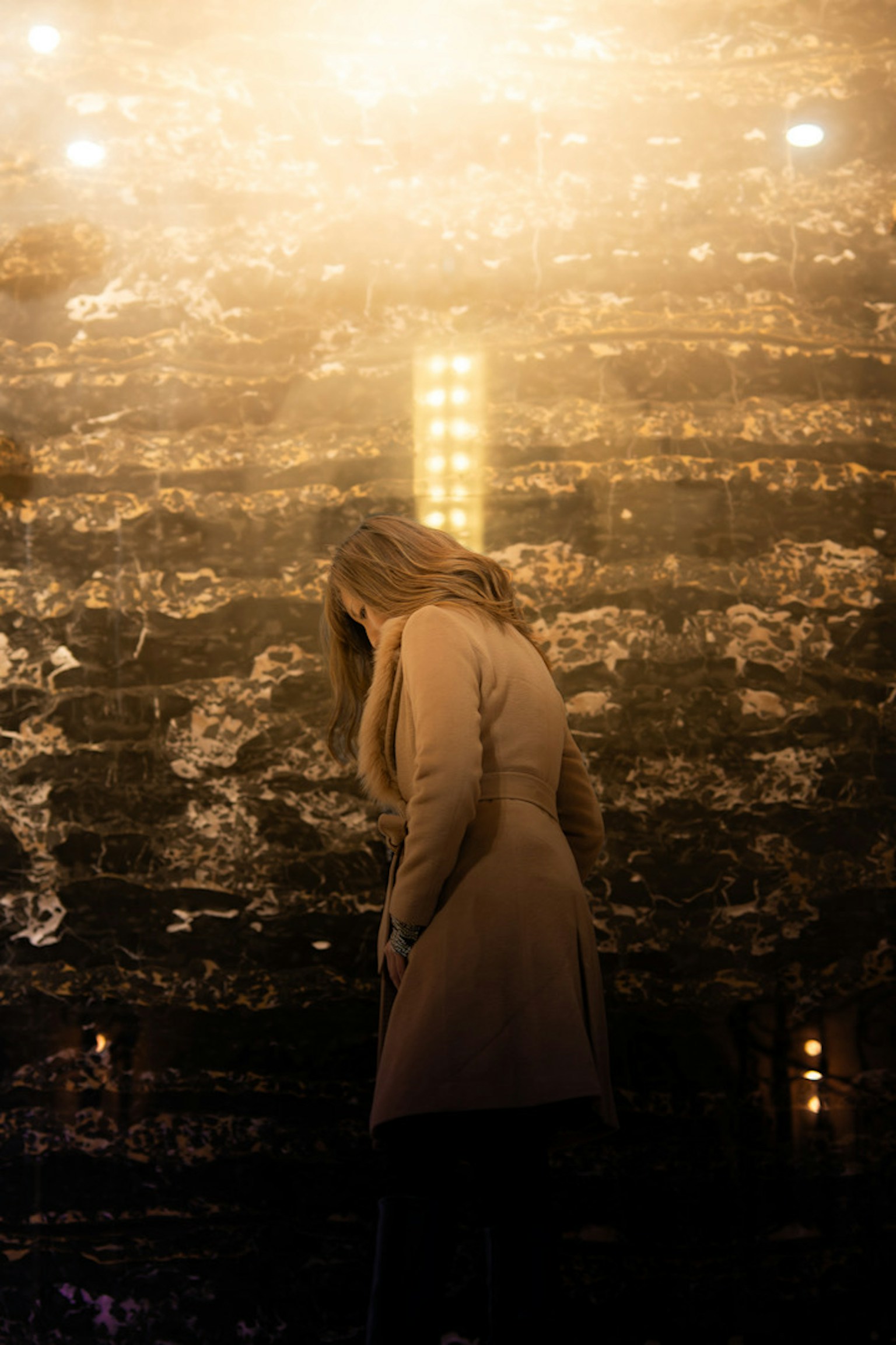 一名女性在明亮的牆前低頭