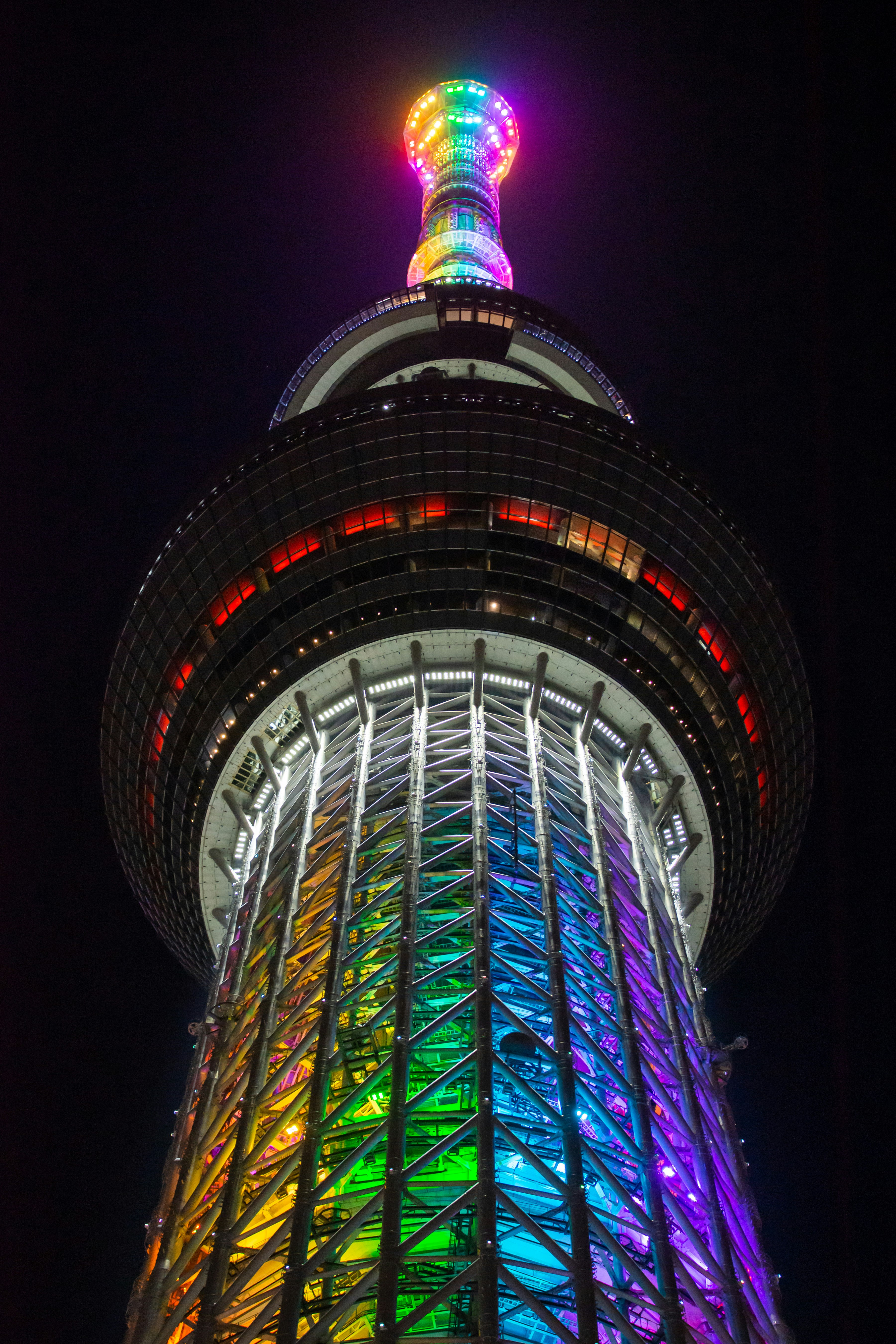 parte superior de una torre iluminada con neones de noche y mirador