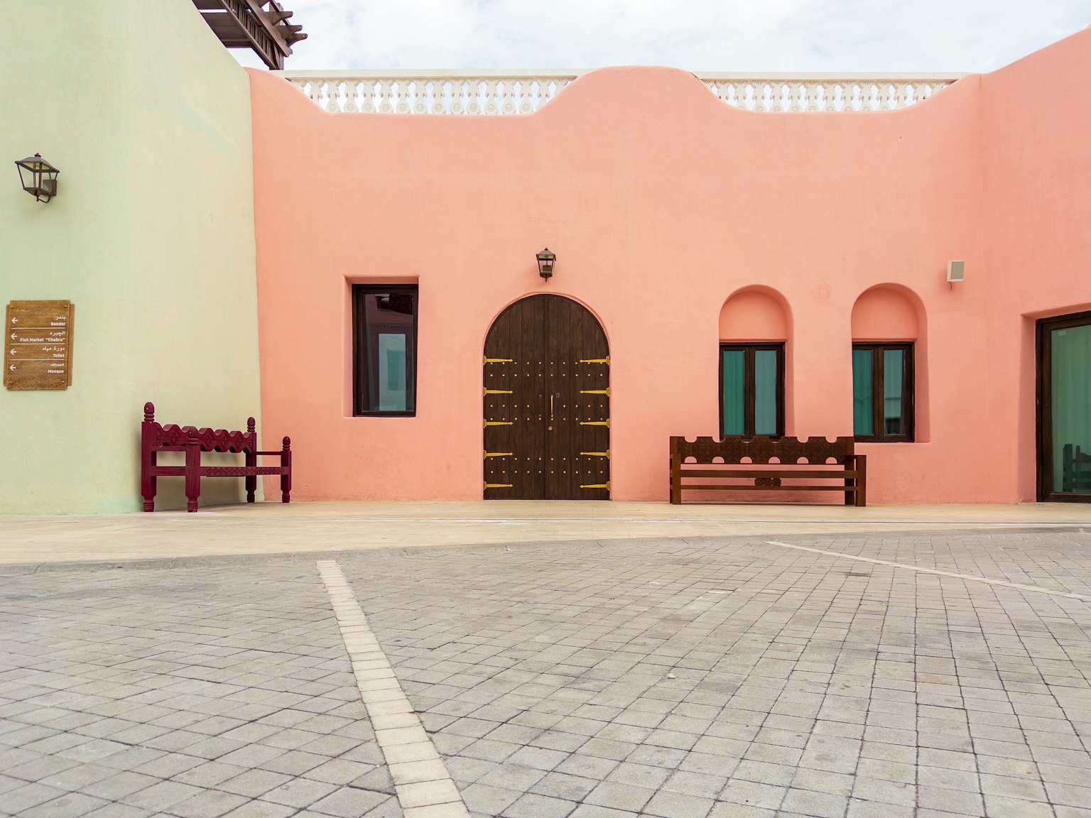 Extérieur d'un bâtiment avec des murs roses et verts présentant une porte arquée et des fenêtres