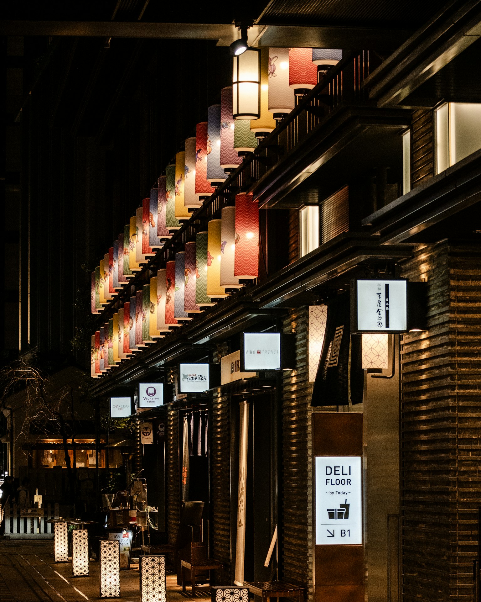 Linternas coloridas y letreros de restaurantes alineados en una calle de la ciudad por la noche