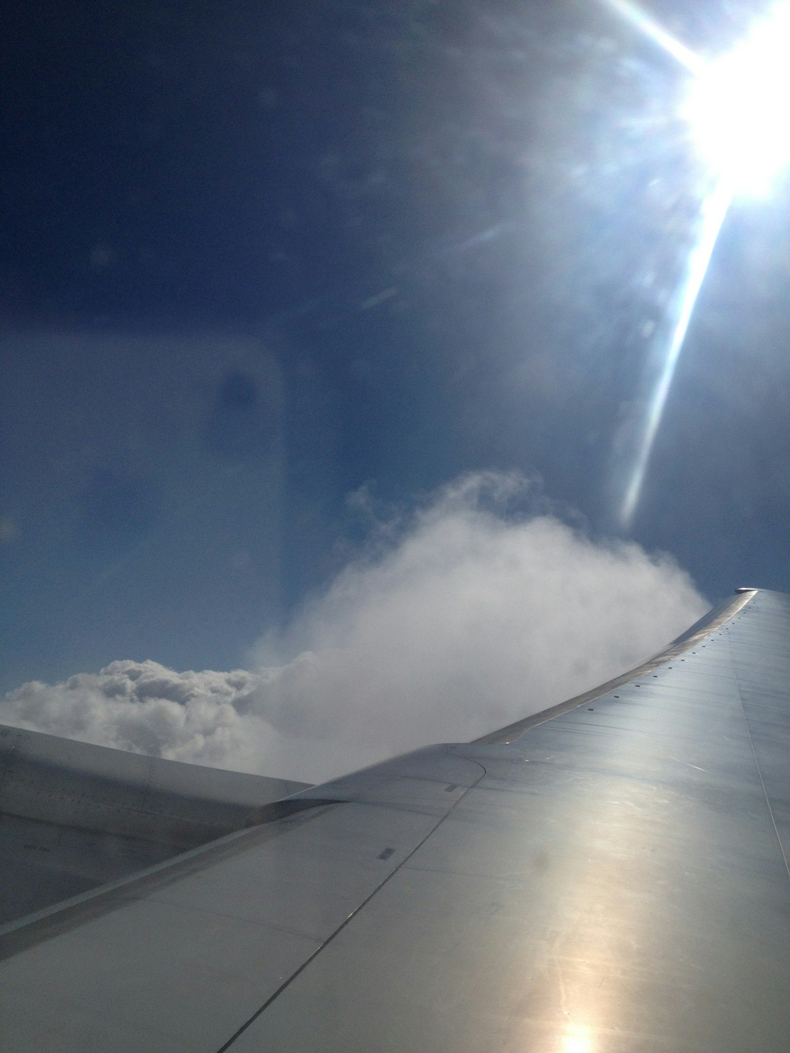 飛機機翼與雲朵和明亮陽光的背景