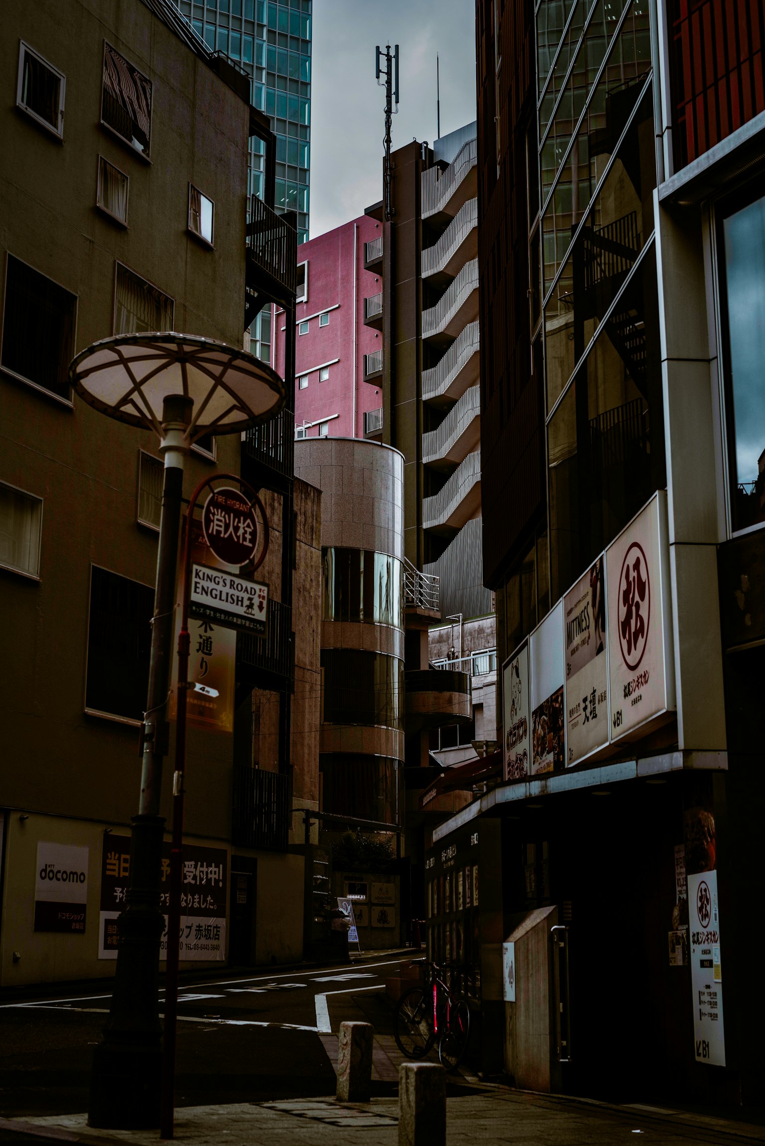 Photo d'une rue sombre avec des bâtiments et des lampadaires présentant des bâtiments hauts et des ruelles étroites