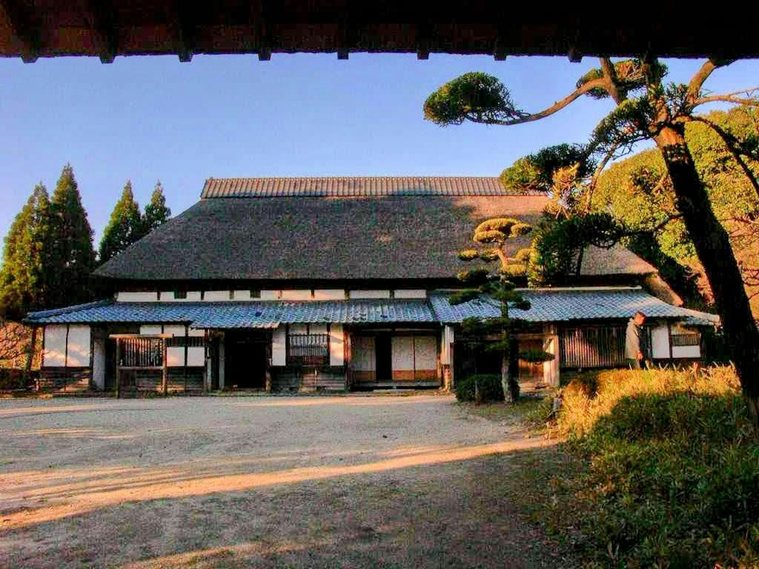 Rumah tradisional Jepang dengan atap jerami dikelilingi pepohonan