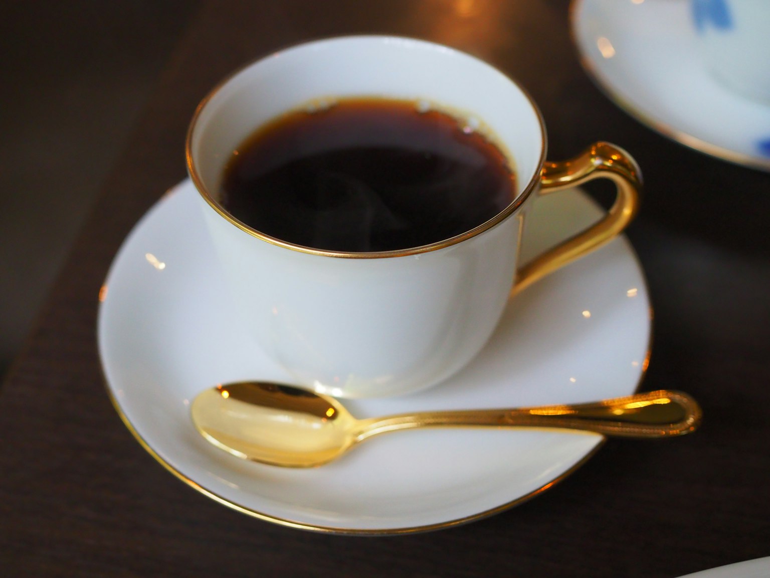 白色杯子裡的咖啡和金色湯匙在茶碟上
