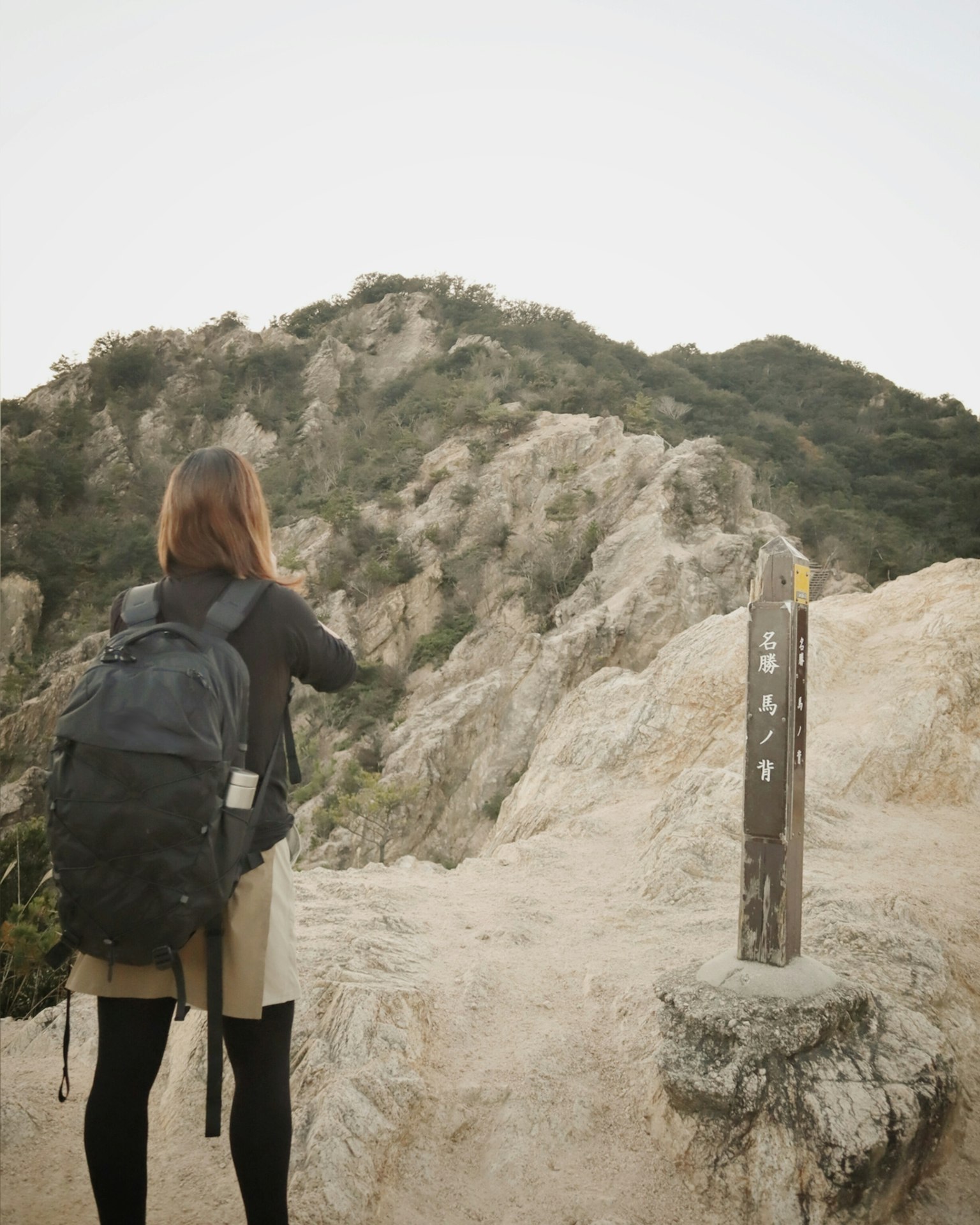 배낭을 멘 여성이 산 경치를 촬영하고 있다