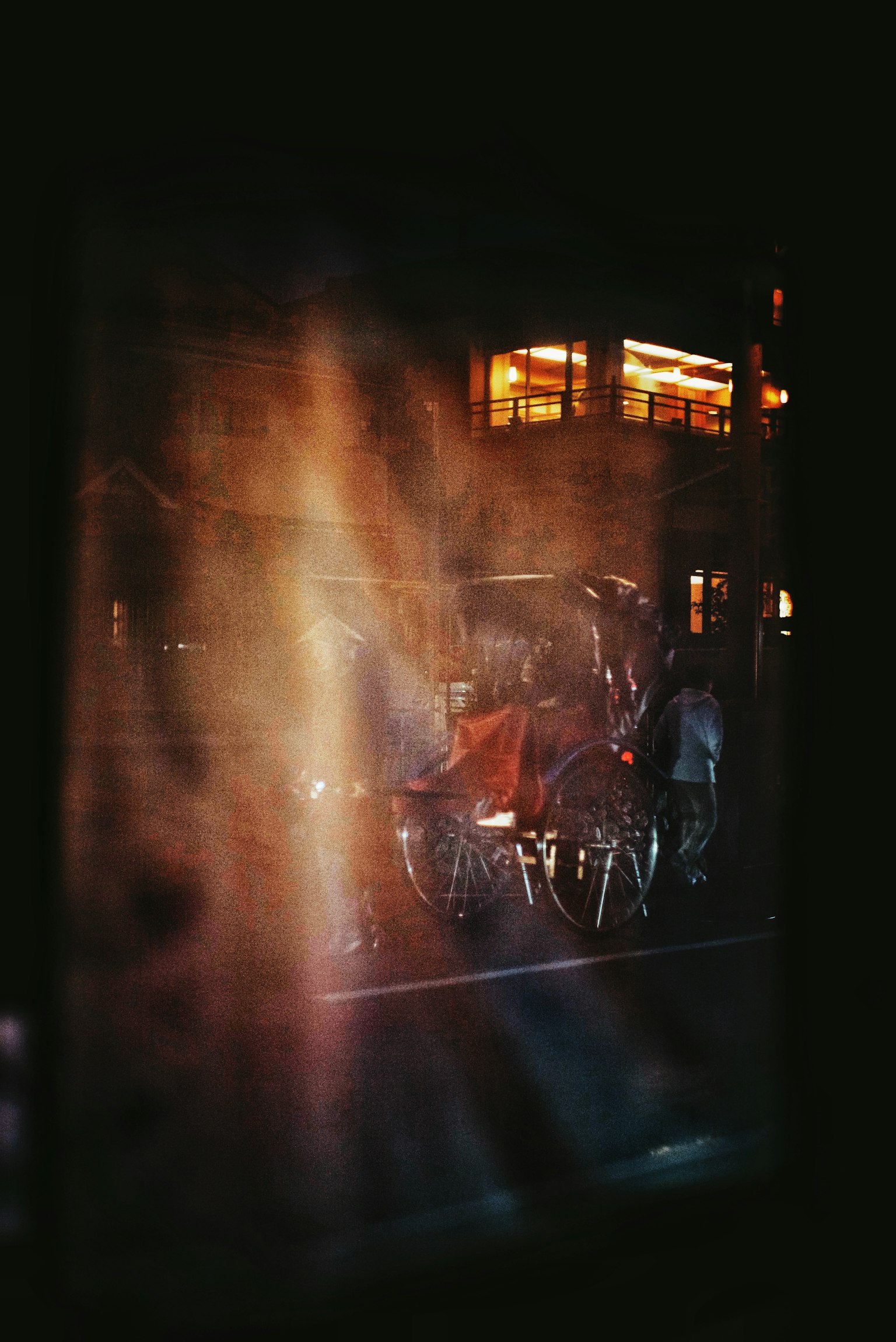 霧のかかった窓越しに見える夜の街の風景と自転車