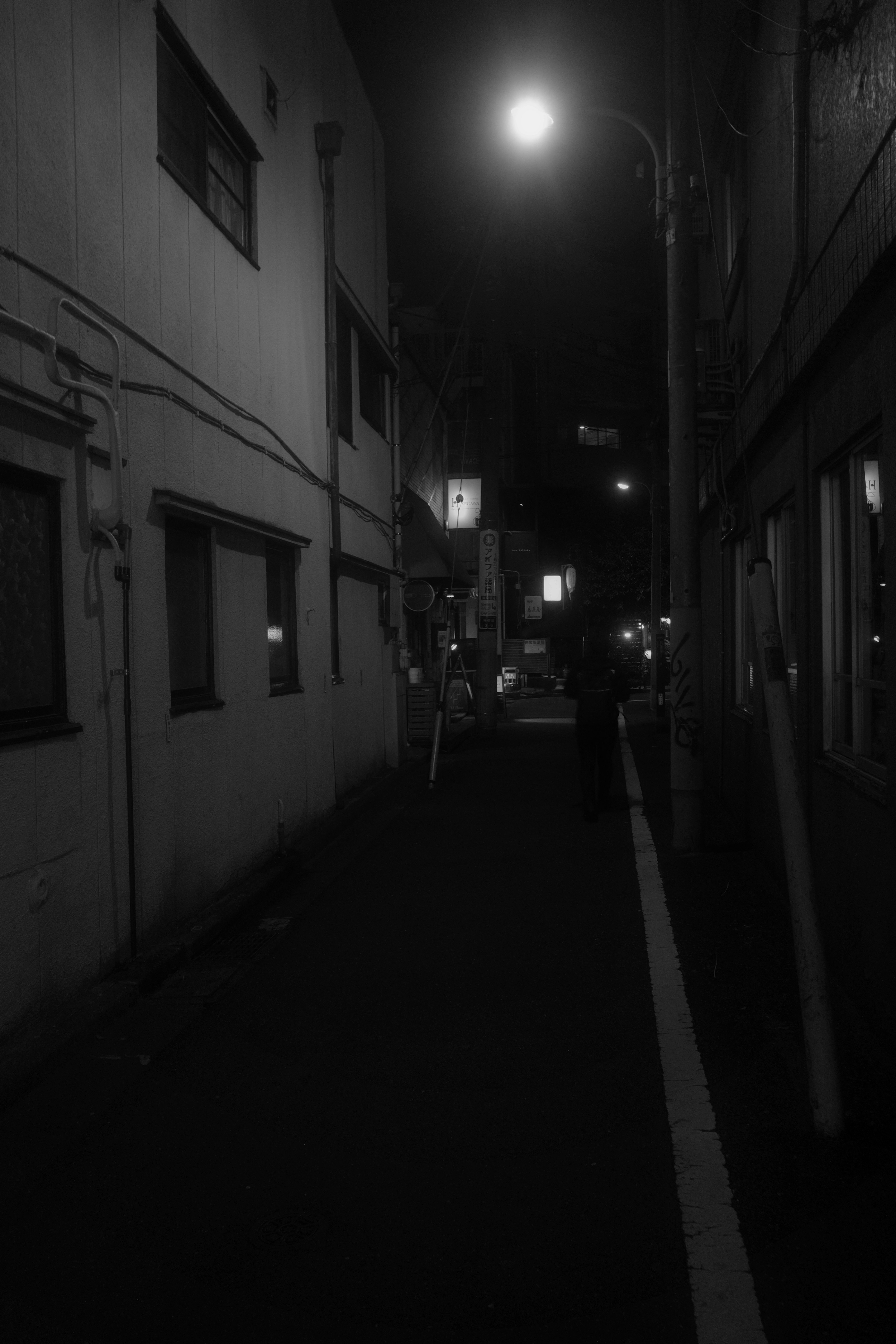 Callejón estrecho con edificios blancos y luz de farola