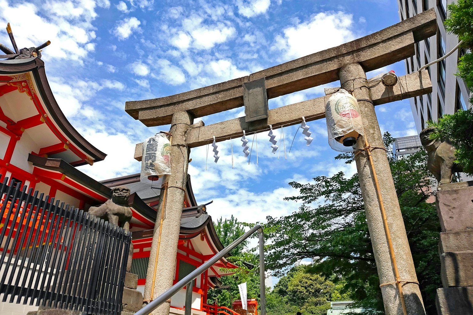 Cổng torii với đền đỏ và bầu trời xanh phía sau